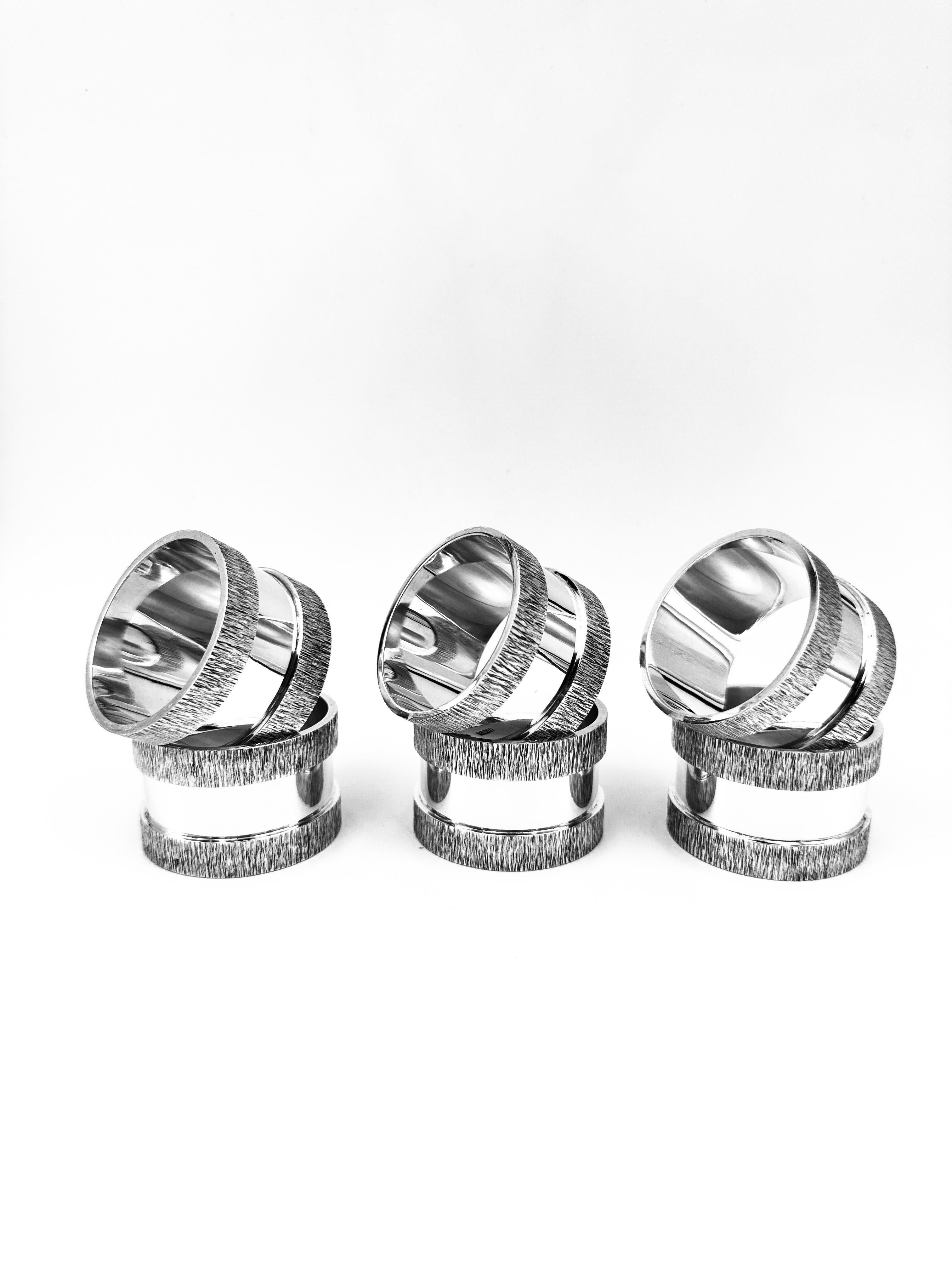 Set di sei portatovaglioli in argento, Londra 1989. La fascia centrale lucida è delimitata da sezioni strutturate con finitura spazzolata. 

Peso: 495,4 g