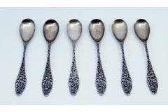 Ensemble de six cuillères à café en argent avec reliefs et poignées découpées.