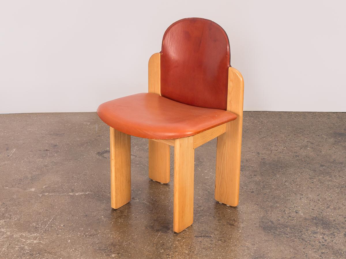 1970s set of six leather dining chairs by Italian designer Silvio Coppola. These cubic, architectural chairs are constructed from ashwood and a warm cognac leather. The flat frames have perpendicular legs, which contrast the rounded edges on the