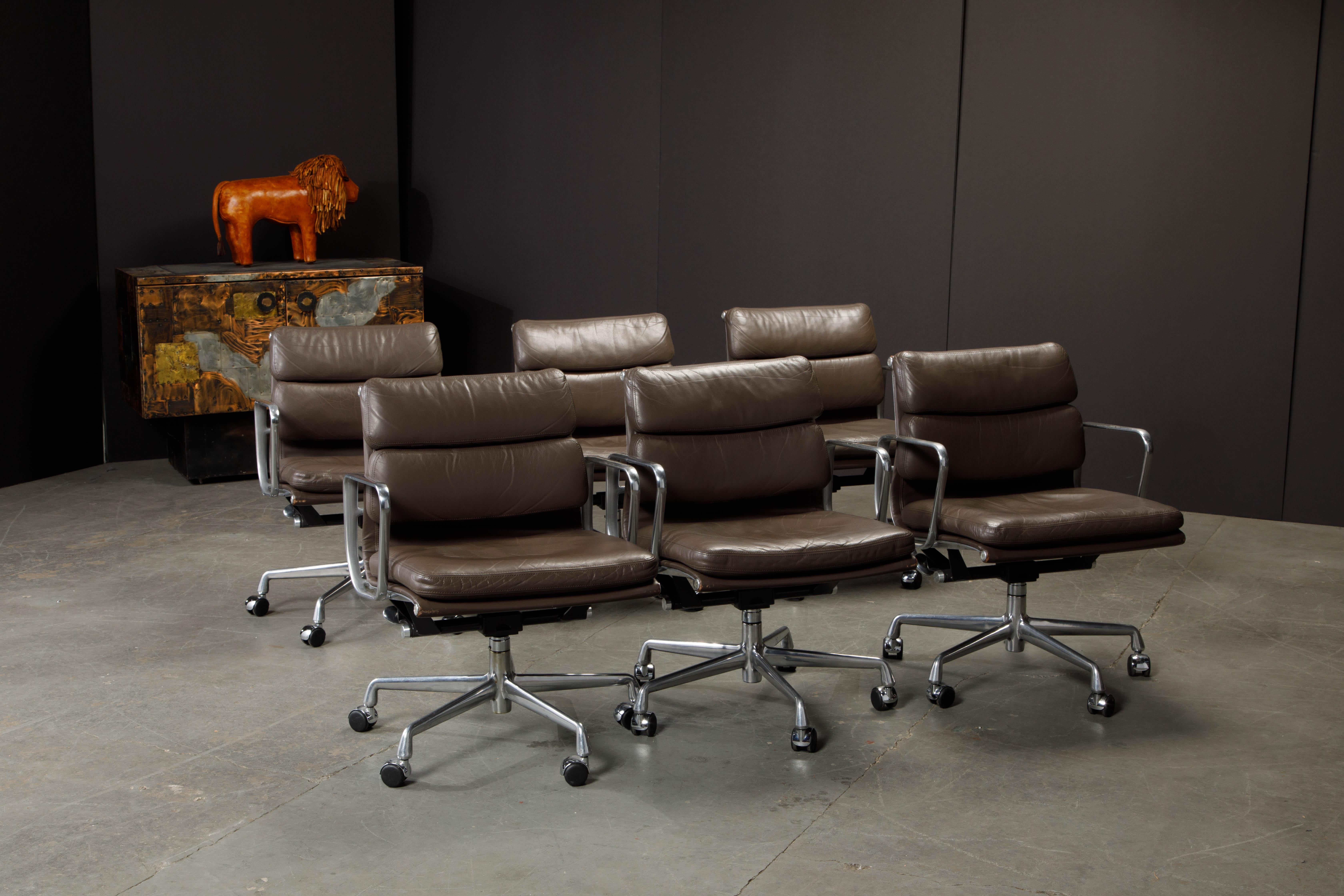 This set of six sought after and in-demand leather desk chairs are the classic 'Soft Pad Management Chair' from the aluminum group line, designed by Charles and Ray Eames for Herman Miller. Featuring their original vintage brown leather upholstery