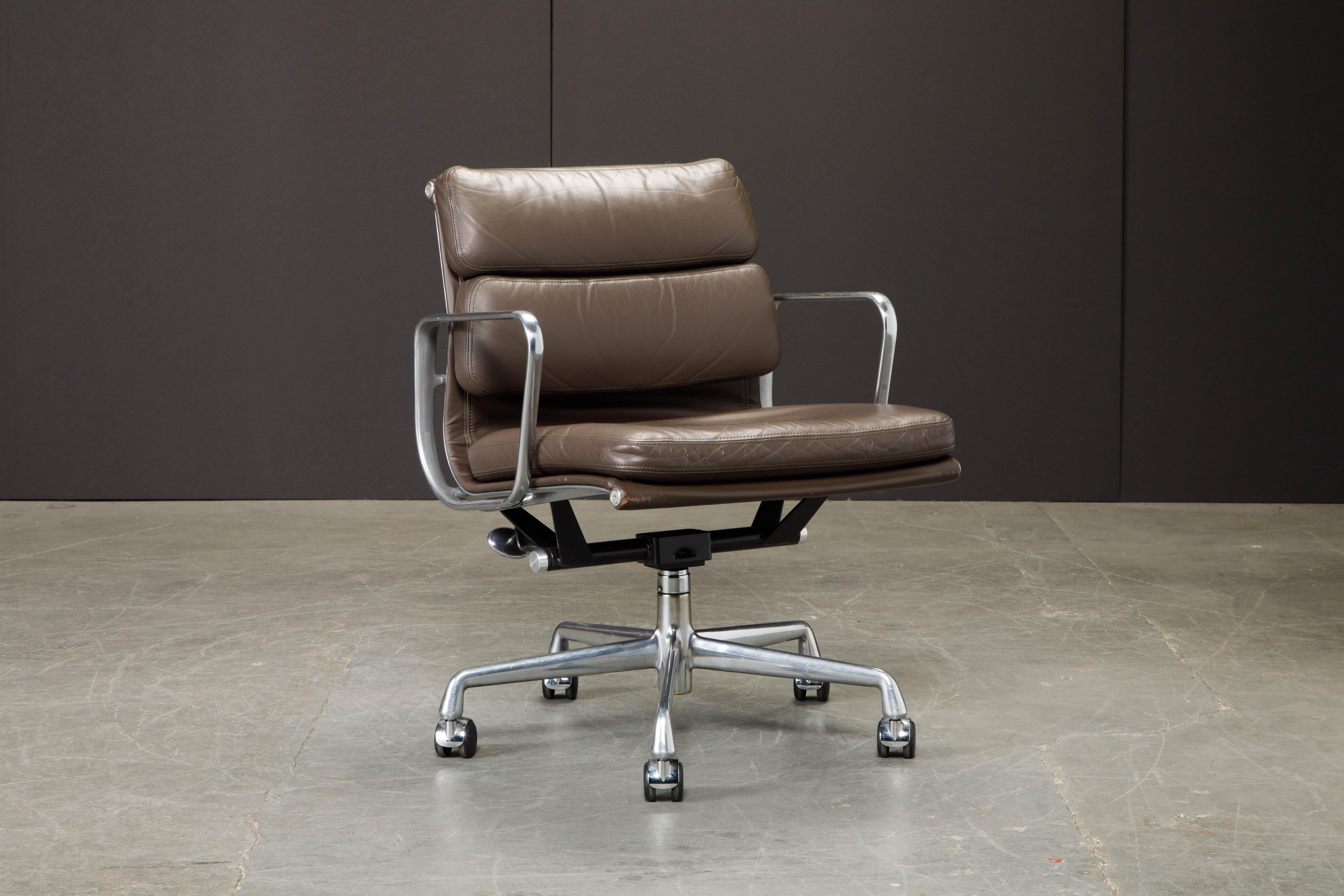 These sought after and in-demand leather desk chairs are the classic 'Soft Pad Management Chair' from the Aluminum Group line, designed by Charles and Ray Eames for Herman Miller. Featuring their original vintage brown leather upholstery over