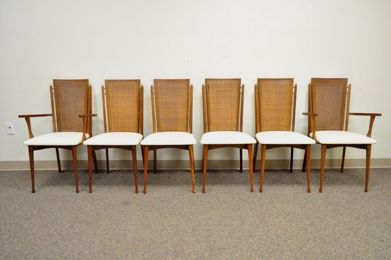 Set of Six vintage Mid-Century Modern Caned Back Dining Chairs by Specialty Woodcraft. Item features 2 Arm Chairs, 4 Side Chairs, Sculptural Solid Teak Frames, Hour Glass Shaped Front Legs, Caned Backs, White Vinyl Upholstery, Original Label. Circa