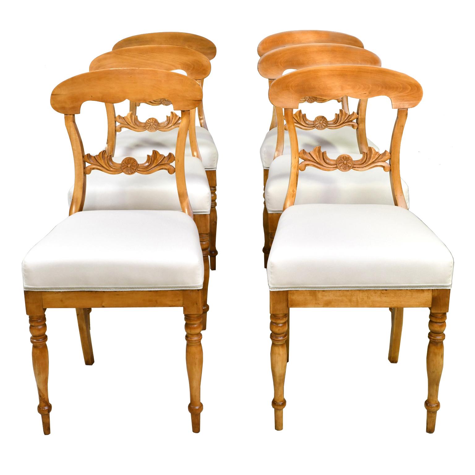 A lovely set of six Karl Johan dining chairs in a light, honey-colored birch wood with newly upholstered seat. Chairs have an arched crest rail, carved acanthus and rosette on back rail, turned front legs and saber rear legs, Sweden, circa 1825.