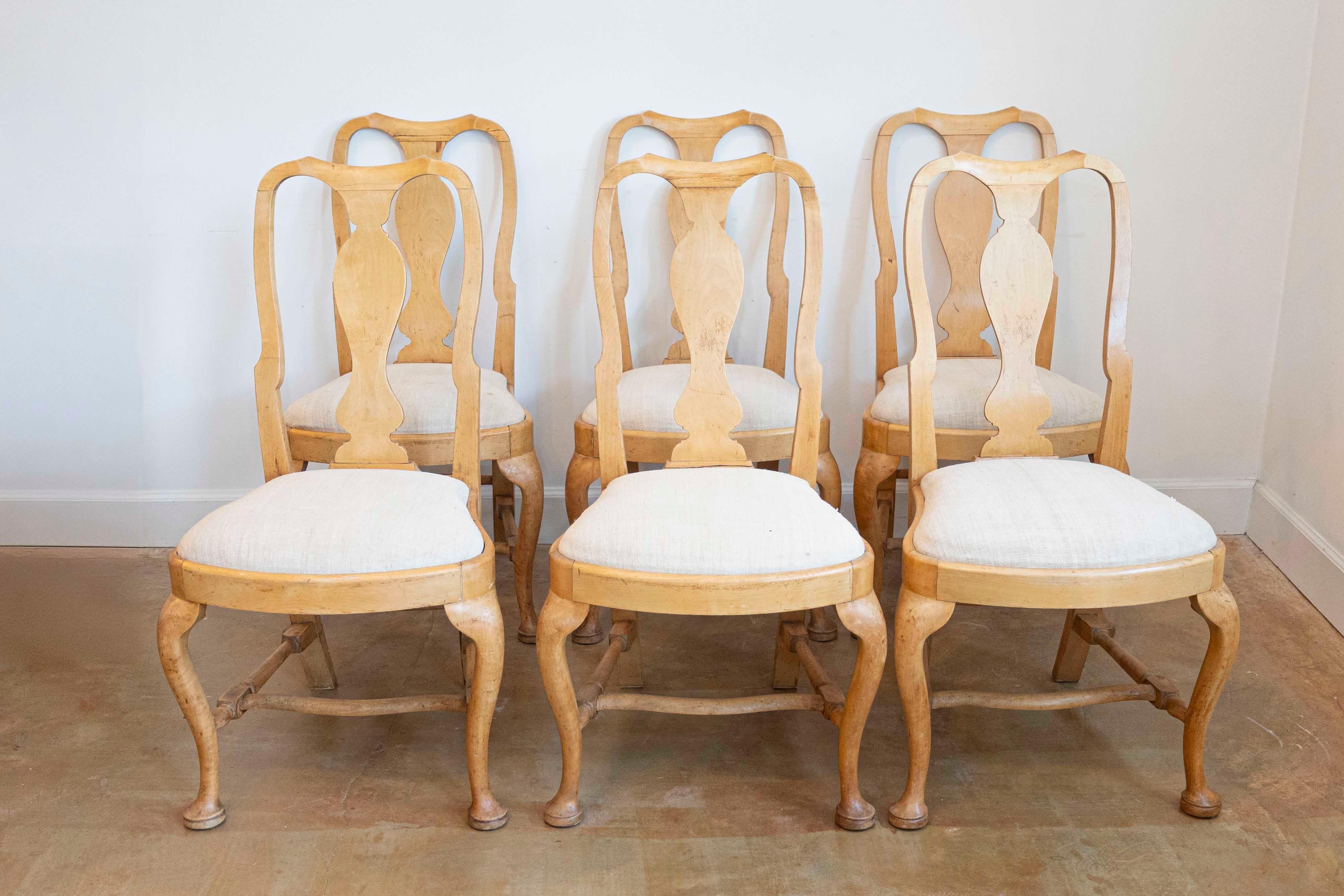 A set of six Swedish Rococo style wooden dining room side chairs from the late 19th century, with carved splats, cabriole legs, pad feet, cross stretchers and upholstered seats. Created in Sweden during the last decade of the 19th century, each of