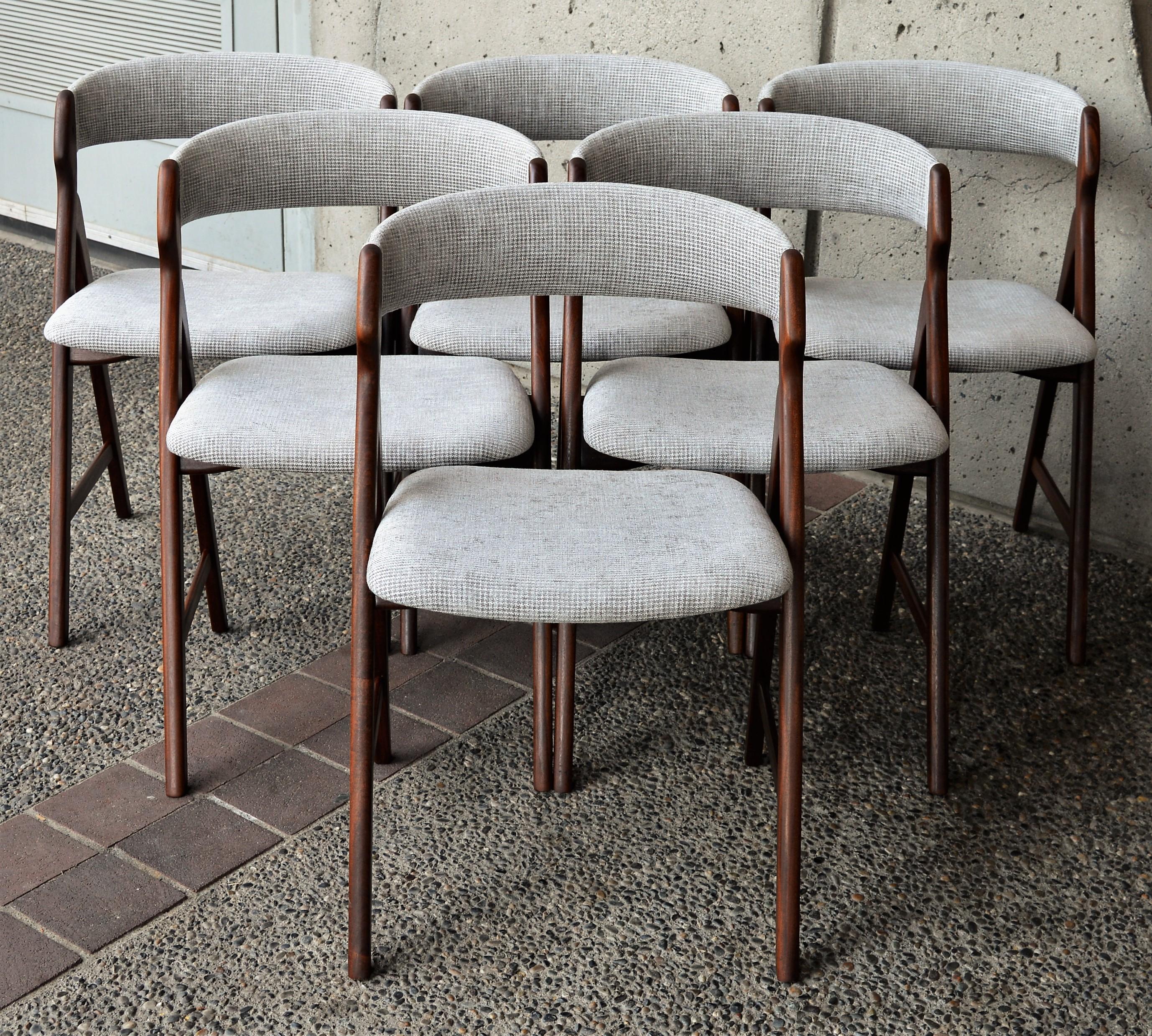 This stellar set of six Danish modern teak dining chairs were designed by T.H. Harlev for Farstrup in the 1960s. Made entirely of solid Afromesia teak, the darker wood tones are perfectly complemented by the new silvery gray small houndstooth plush