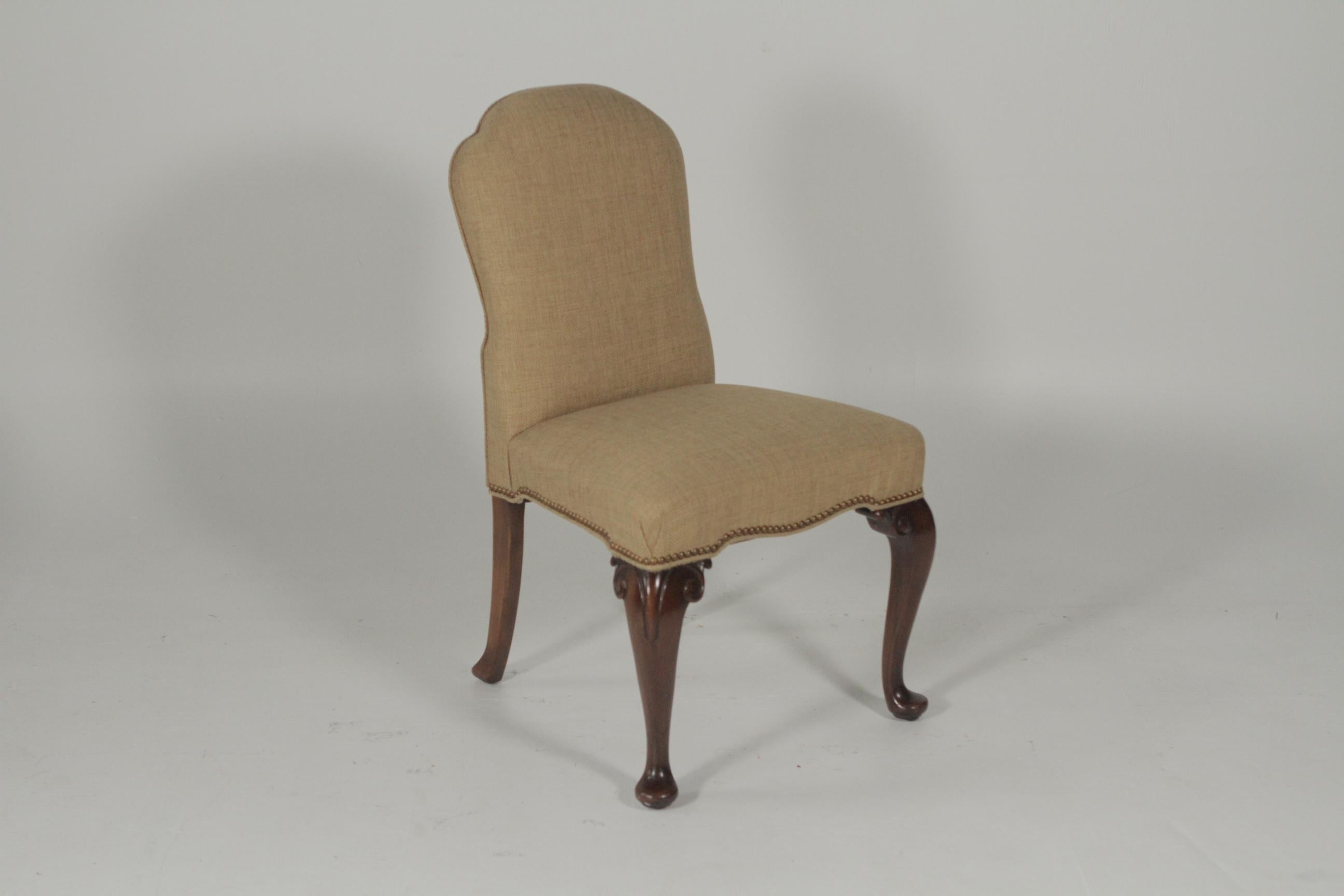 A set of six shapely dining chairs newly upholstered in a rustic cotton linen woven fabric by Farrell. The carved legs with brass nailhead trim all around. The fabric is soft to the touch and in a light neutral camel color.