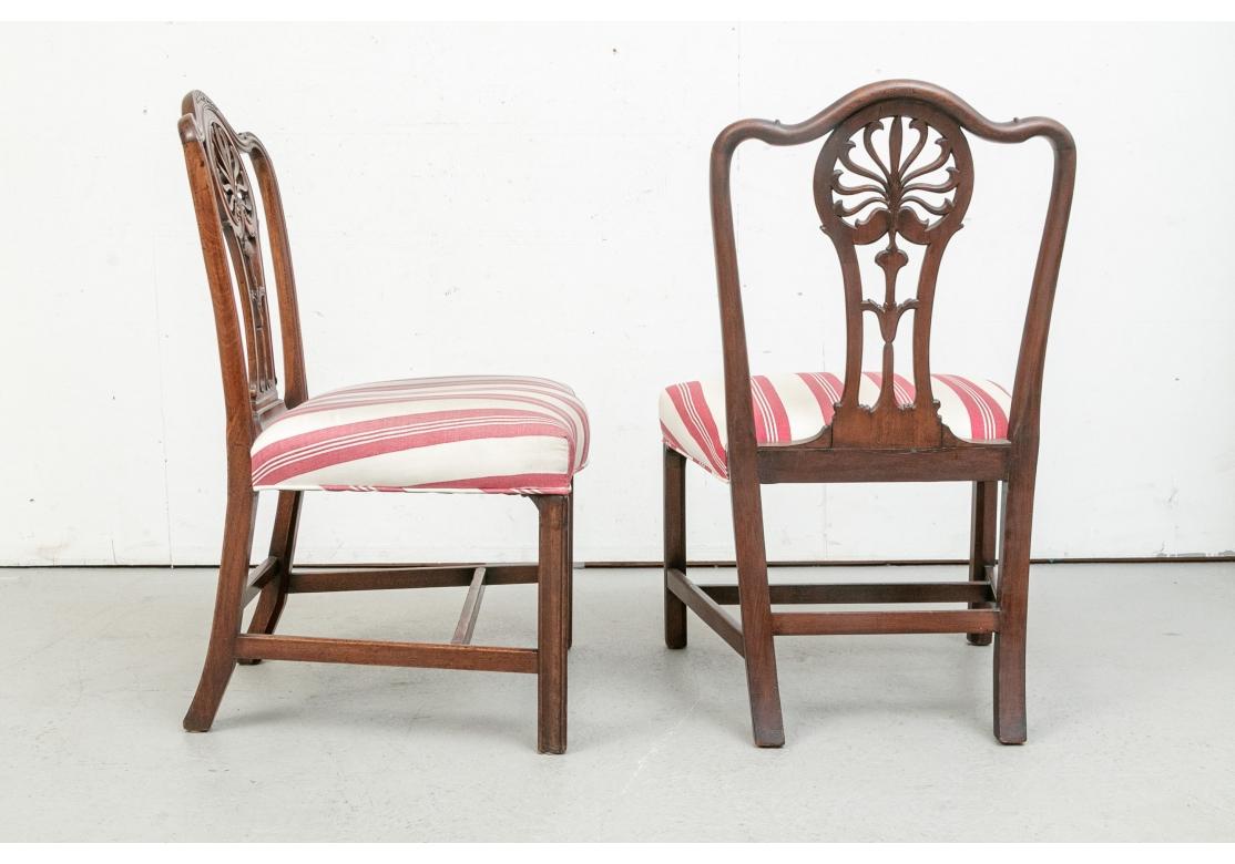 A set of six very well-made dining chairs with elaborately carved backs plate having a central flower design with flower carved crest, generous Serpentine front seats, H-Form stretcher base and straight fluted legs. Custom upholstered in a wide