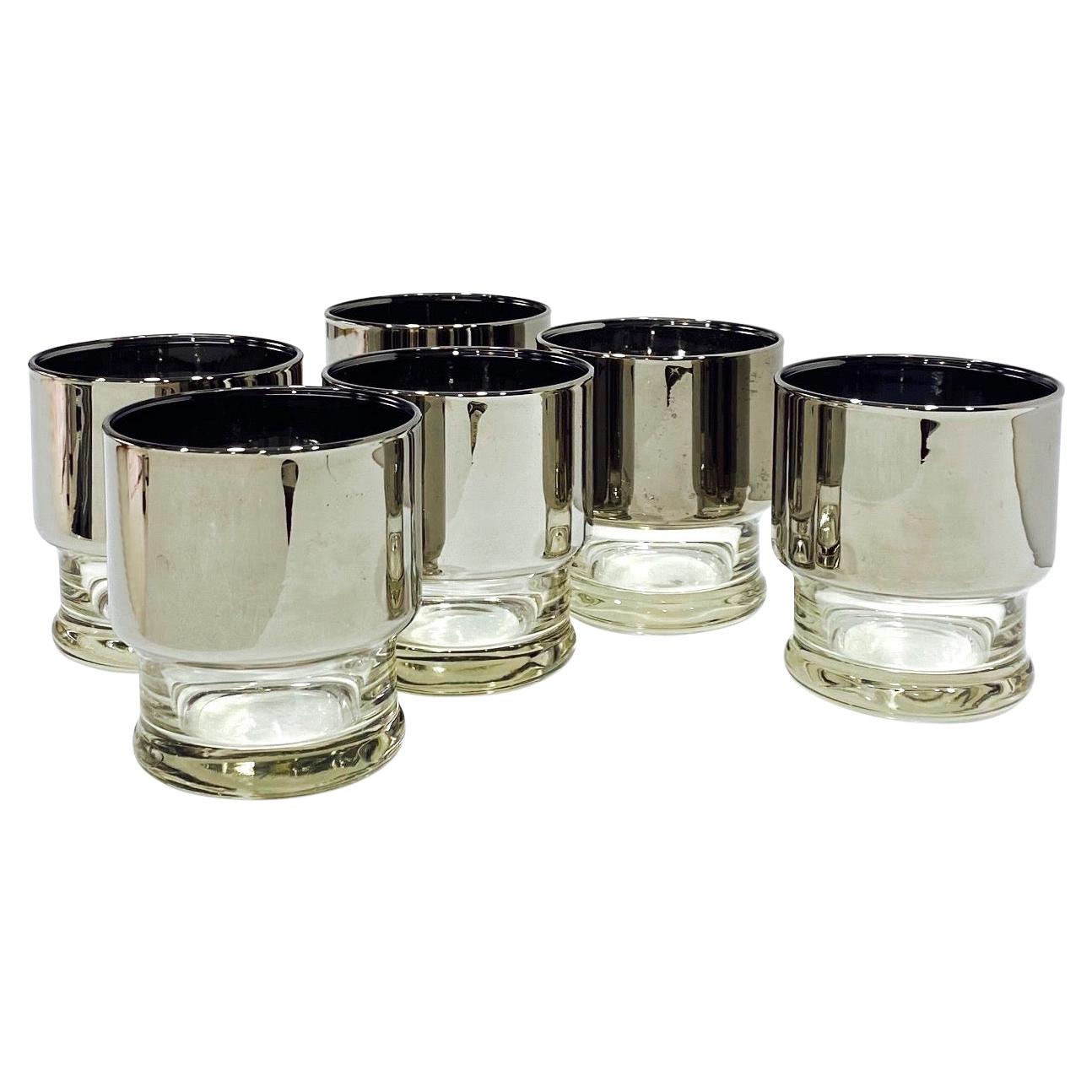 Mid-Century Modern whiskey rock glasses with bands of thick silver overlay. The silver ombre covers the top portion of the glasses which fades into the tapered clear glass bases. These iconic barware glasses make a cheerful and chic addition to any
