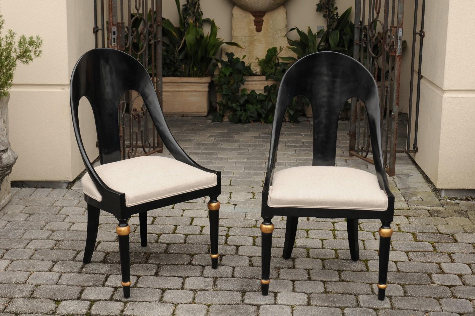 A set of six vintage ebonized wood spoon back chairs from the mid-20th century with newly upholstered seats and gilt accents. Born during the midcentury period, each of this set of six dining chairs features a spoon back, flowing seamlessly into two