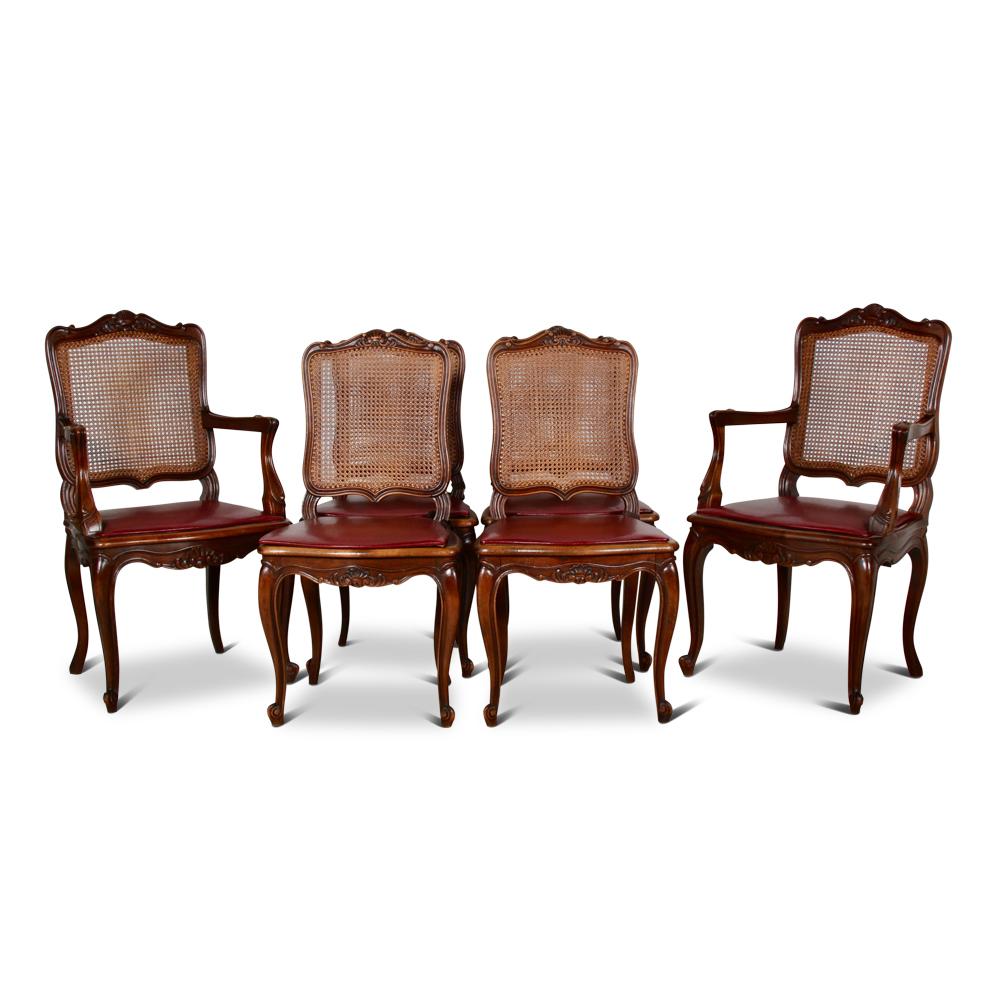 A set of six French carved cherry Louis XV style dining chairs consisting of four side chairs and two armchairs.

Hand carved frames and caned backs and seats, the seats with thin upholstered cushions.

Caning in excellent condition.

Side