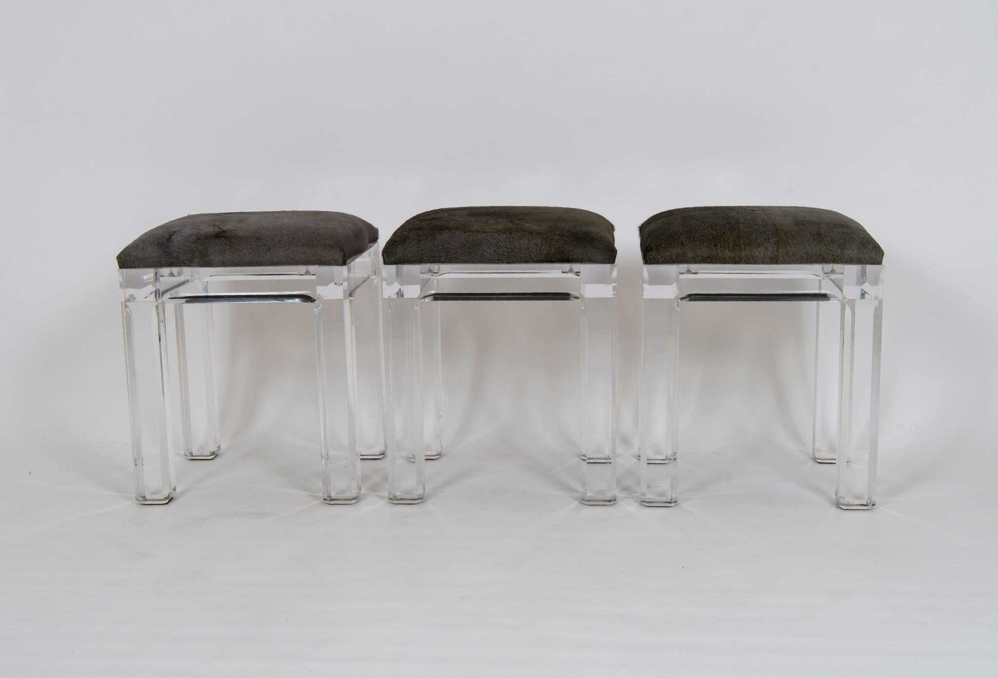 A set of six vintage Lucite counter stools with sturdy block bevelled legs and newly upholstered in an acid dyed Italian hair hide. These hides read a silver charcoal gray with slight green blue undertones.