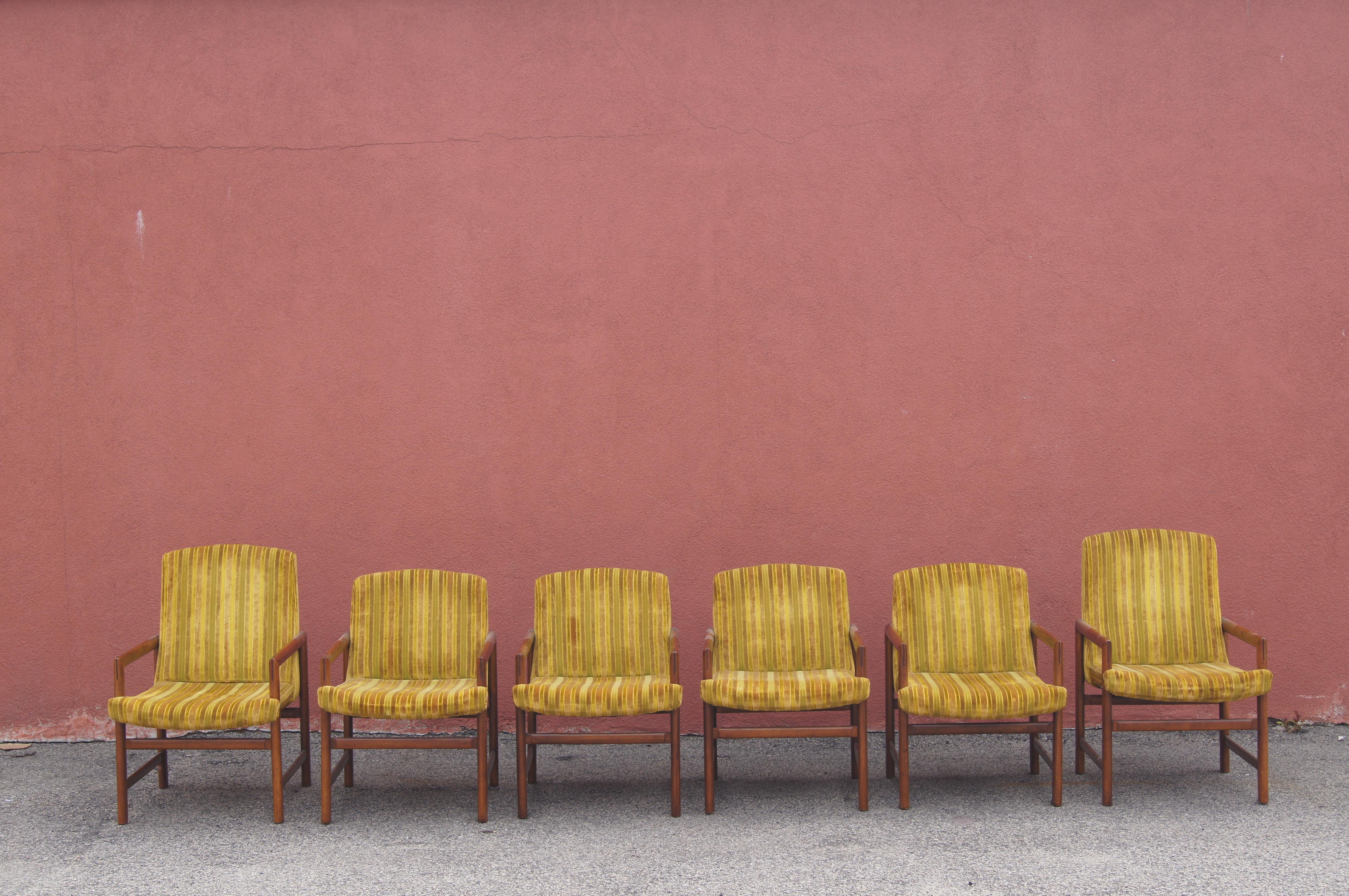 Sold in the late 1950s by Rapids Furniture of Boston, this set of mid-century dining chairs comprises six upholstered armchairs whose solid walnut frames feature handsome joinery details. 

The dimensions below reflect the correct dimensions for