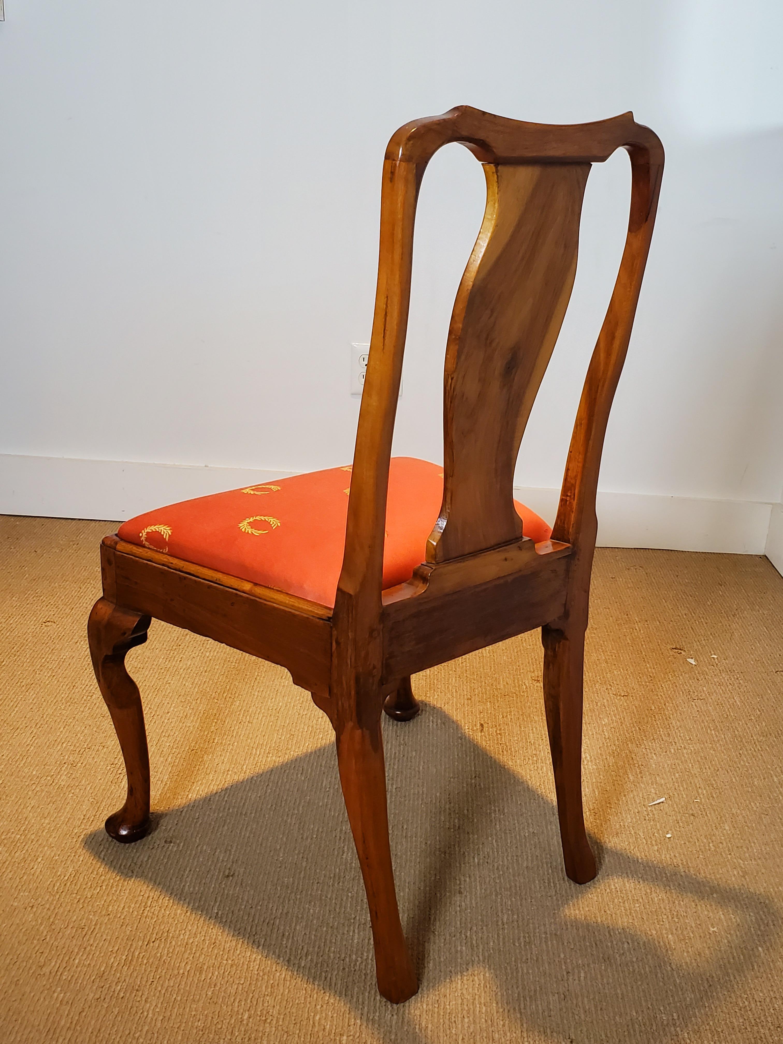 A set of six hand carved walnut Queen Anne dining chairs. The graceful lines with an warm patination with concave crests, vase form splats with slip seats resting on cabriole legs. The seats covered and a beautiful vibrant salmon color wreath damask