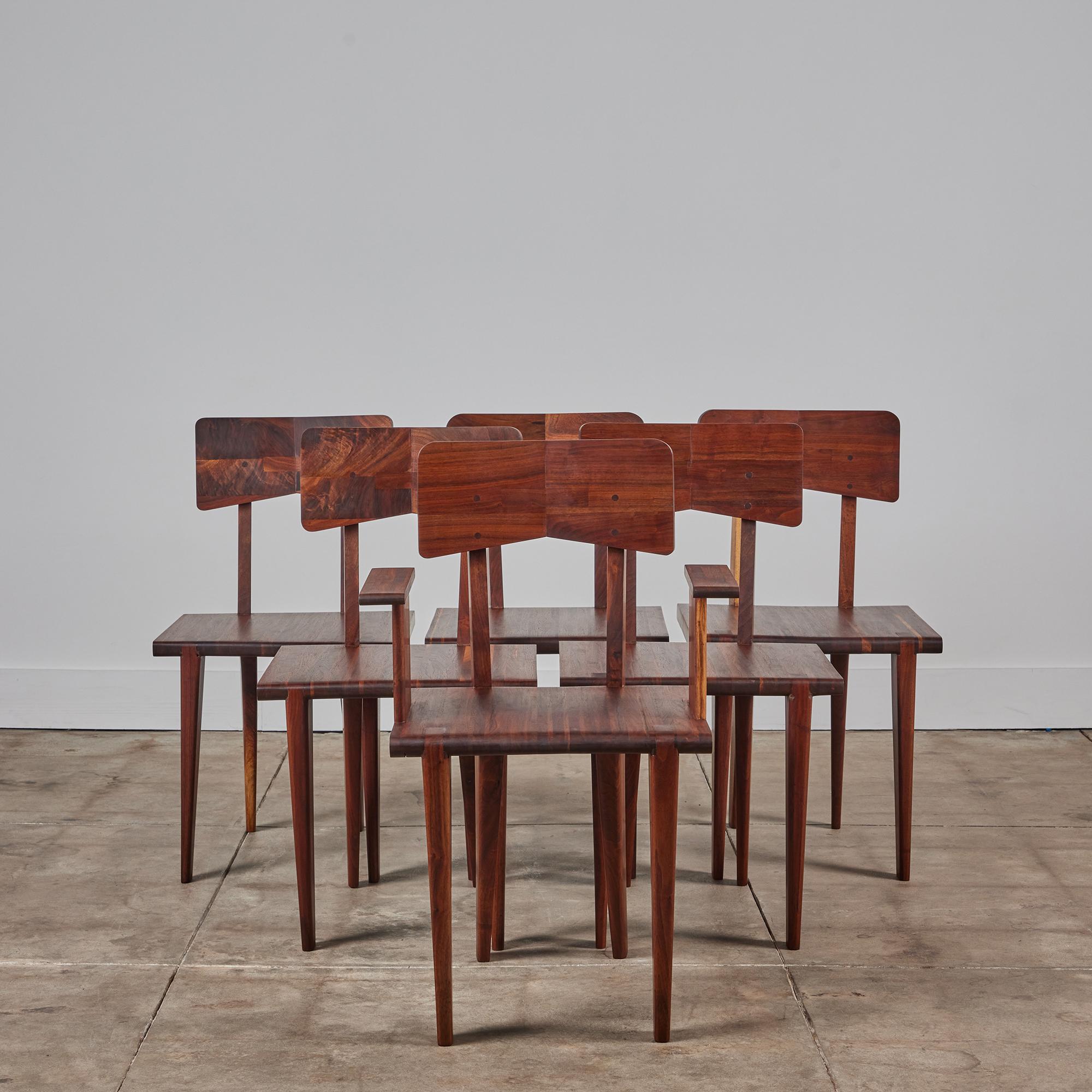 Designed in the style of French designer Jean Prouvé, this set of six studio craft dining chairs feature a solid walnut frame and beautiful geometric lines. Each unique seatback showcases beautiful dowel work that can also be seen on the side of