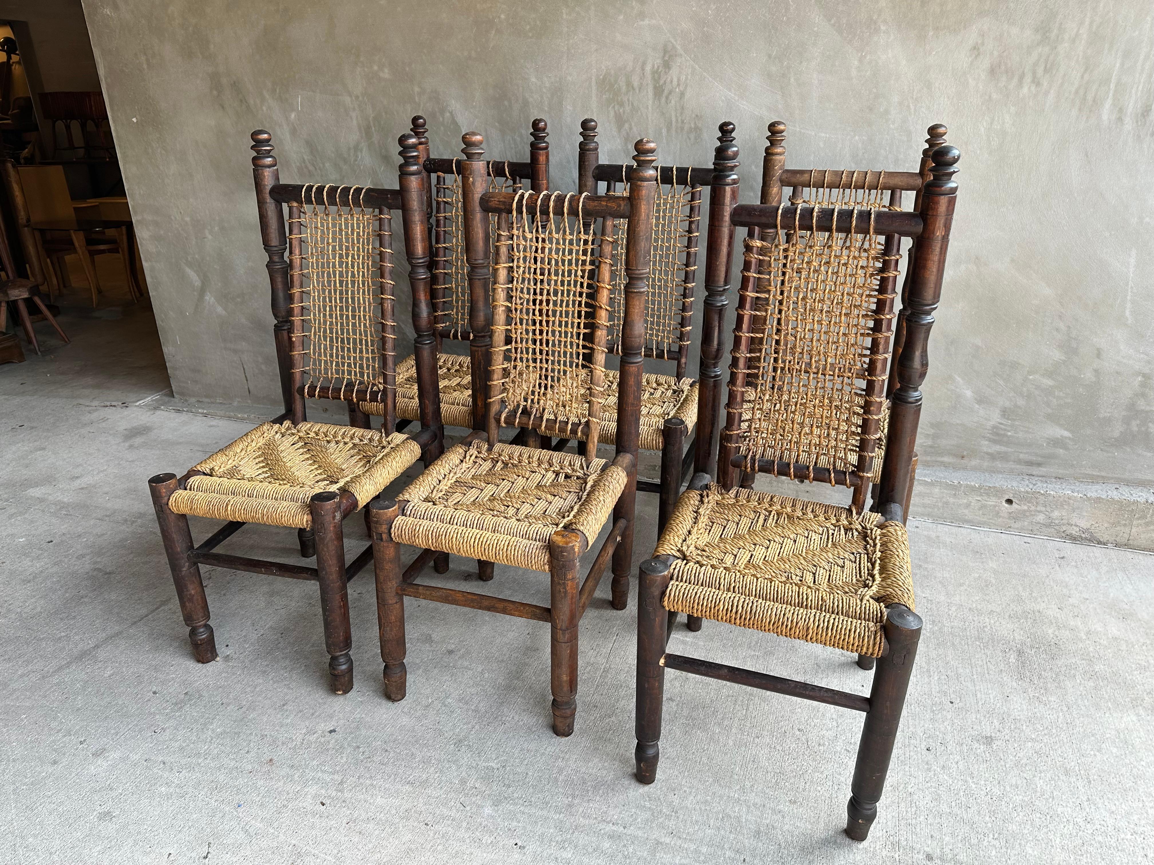 The South of France was home to the finest woven rope and rush furniture in the mid 20th century. Weaving artisans like Audoux and Minet are now highly sought after. This fine set of six high back dining chairs is in that tradition. Dark beech lathe