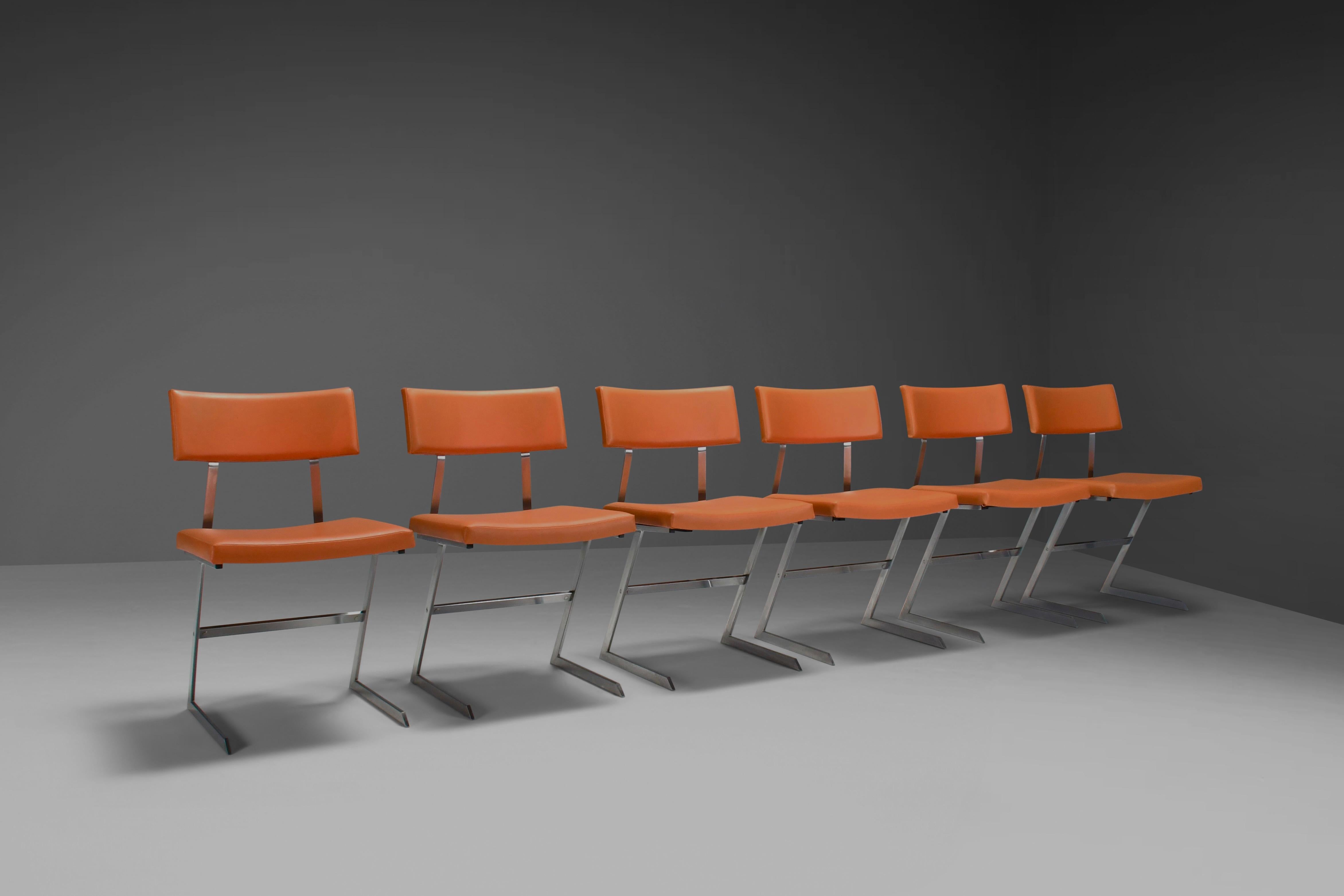 Ensemble de six chaises de salle à manger 'Zig Zag' en très bon état.

Ces chaises se distinguent par leur piétement en forme de Z en métal poli.

Les sièges et les dossiers sont recouverts d'un similicuir orange, offrant à la fois une sensation de