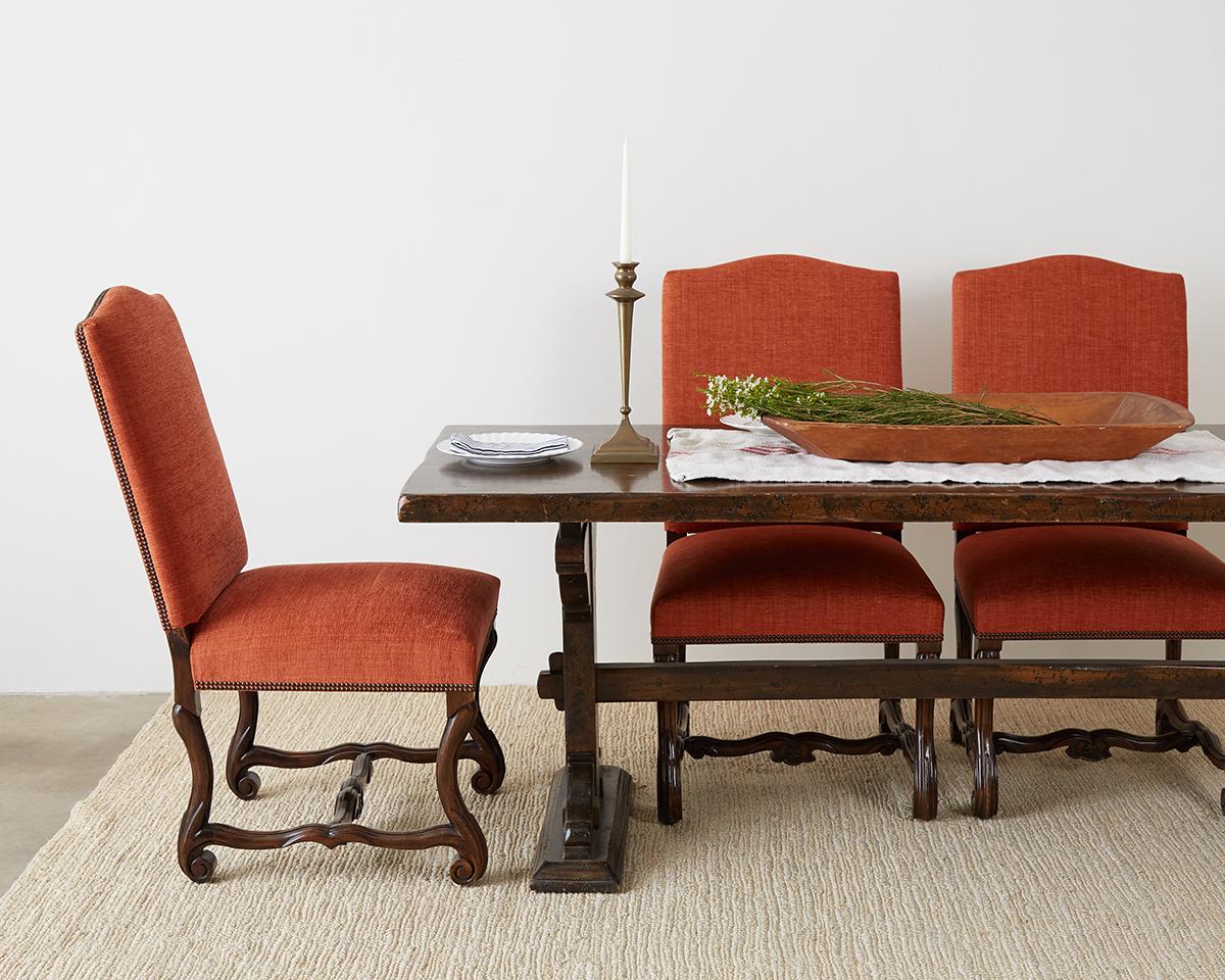 Amazing set of sixteen French Louis XIII Os De Mouton style dining chairs. Finely crafted hand-carved legs conjoined with stretchers supporting an upholstered frame. The seat and back have a recent upholstery redux in a stylish paprika colored