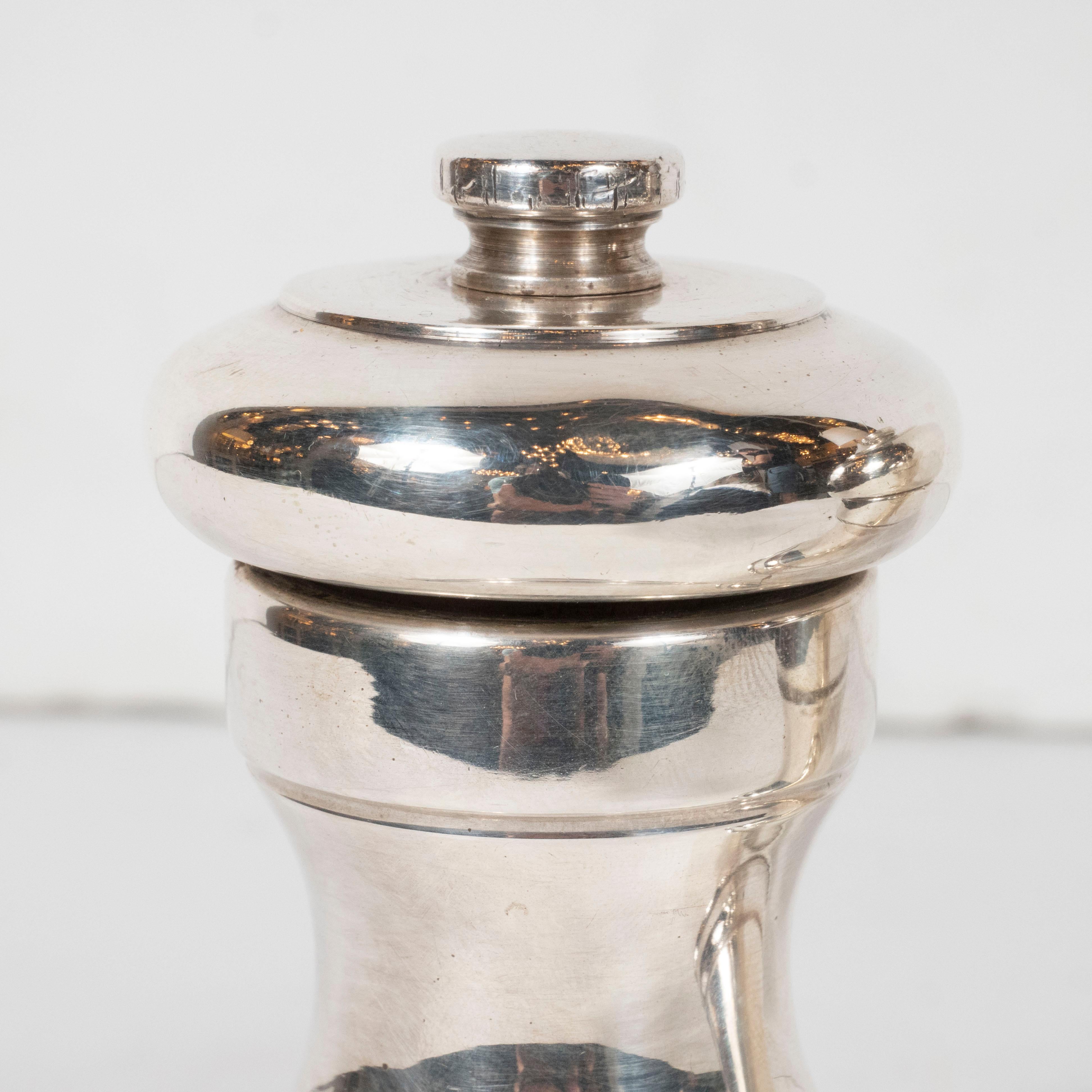 This elegant Mid-Century Modern salt and pepper shaker sterling silver salt and pepper shaker set were realized by the esteemed design firm Peugot in France, circa 1960. They feature hourglass form stepped bodies with finials at the top of each in
