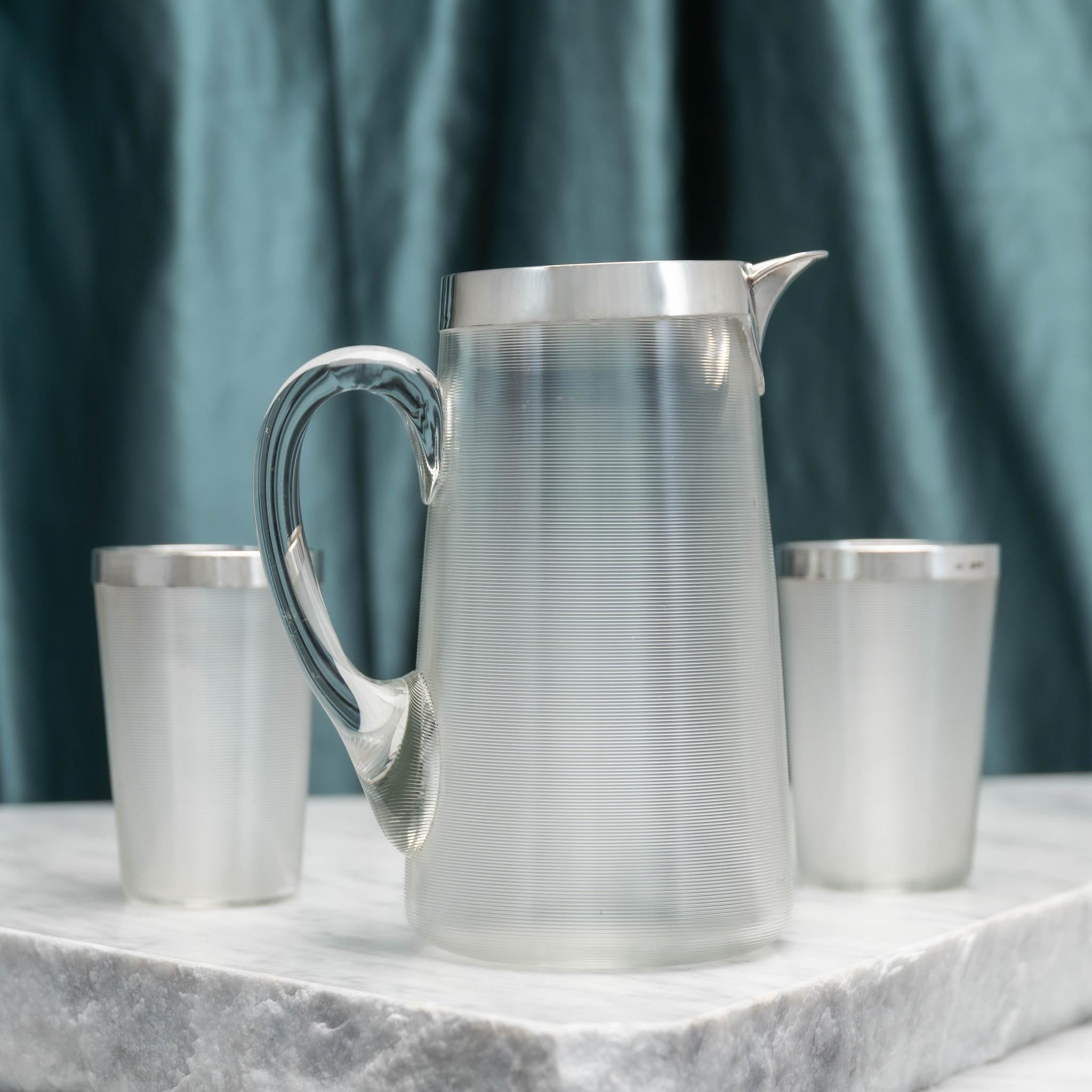 Ein Paar Trinkbecher aus Glas und eine passende Kanne. Alle mit Silberkragen, gestempelt London 1883. Verwendung des gleichen Glastyps wie bei den Zündhölzern, um einen dekorativen Effekt zu erzielen. Das Silber ist auch mit der Herstellermarke des