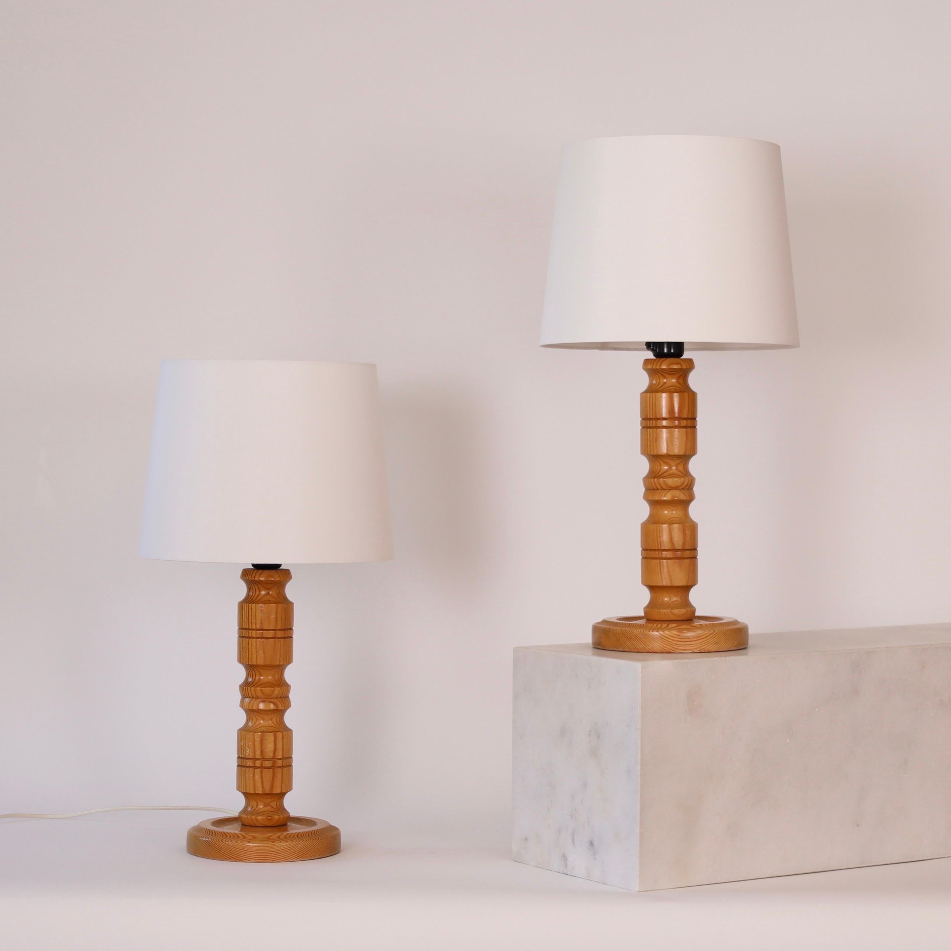 Ensemble de lampes de table suédoises en bois de pin. Une touche scandinave pour une belle maison.

* Paire (2) de lampes de table en pin avec abat-jour en tissu blanc
* Pays : Suède 
* Année : vers les années 1980
* Condition : Bon état vintage.