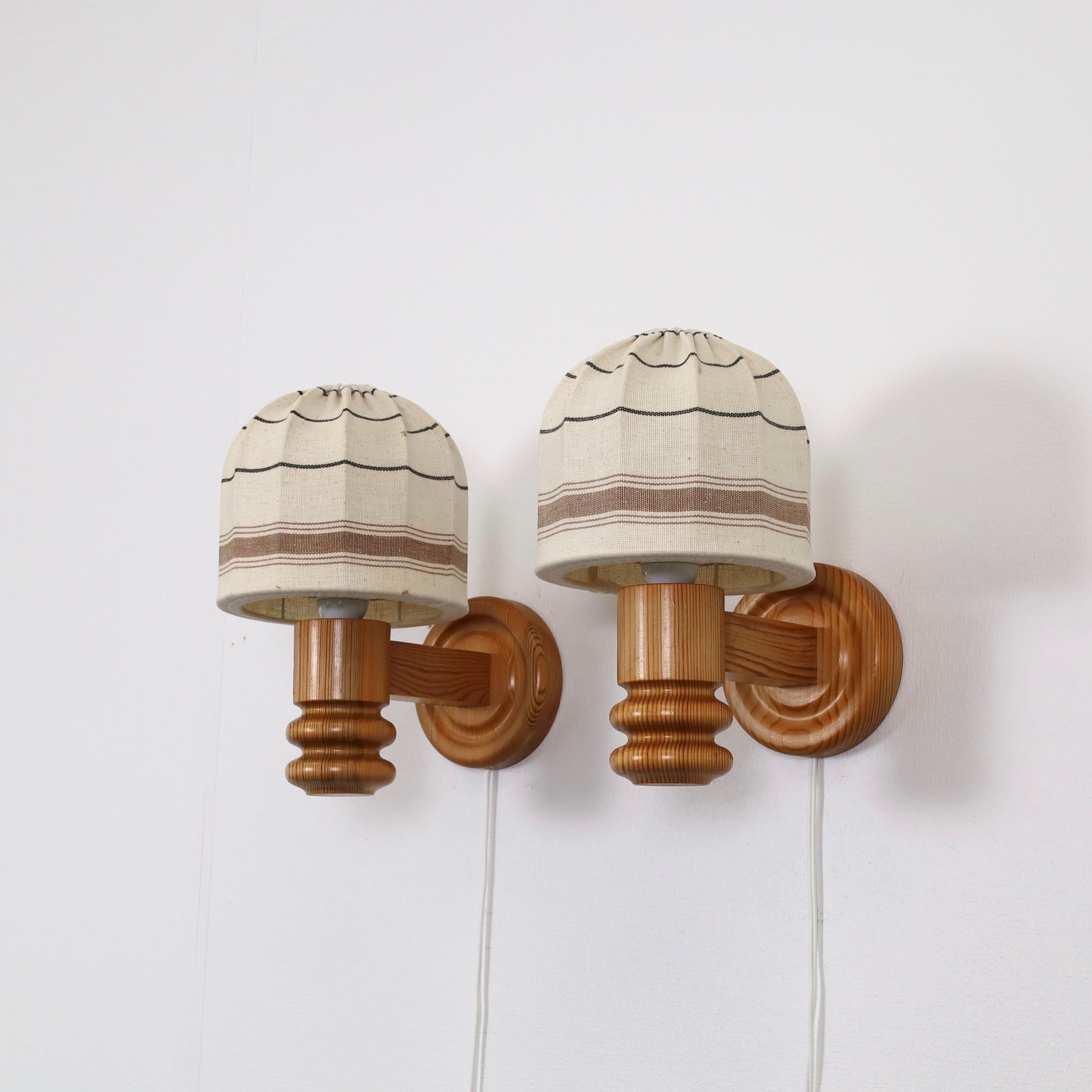 Set Swedish Modern Pine wood Wall lamps made by Solbackens Svarveri in the 1970s. A Scandinavian touch to a beautiful home.

* A pair (2) of Pine wood sconces with the original beige fabric shades with brown lines.
* Manufacturer: Solbackens