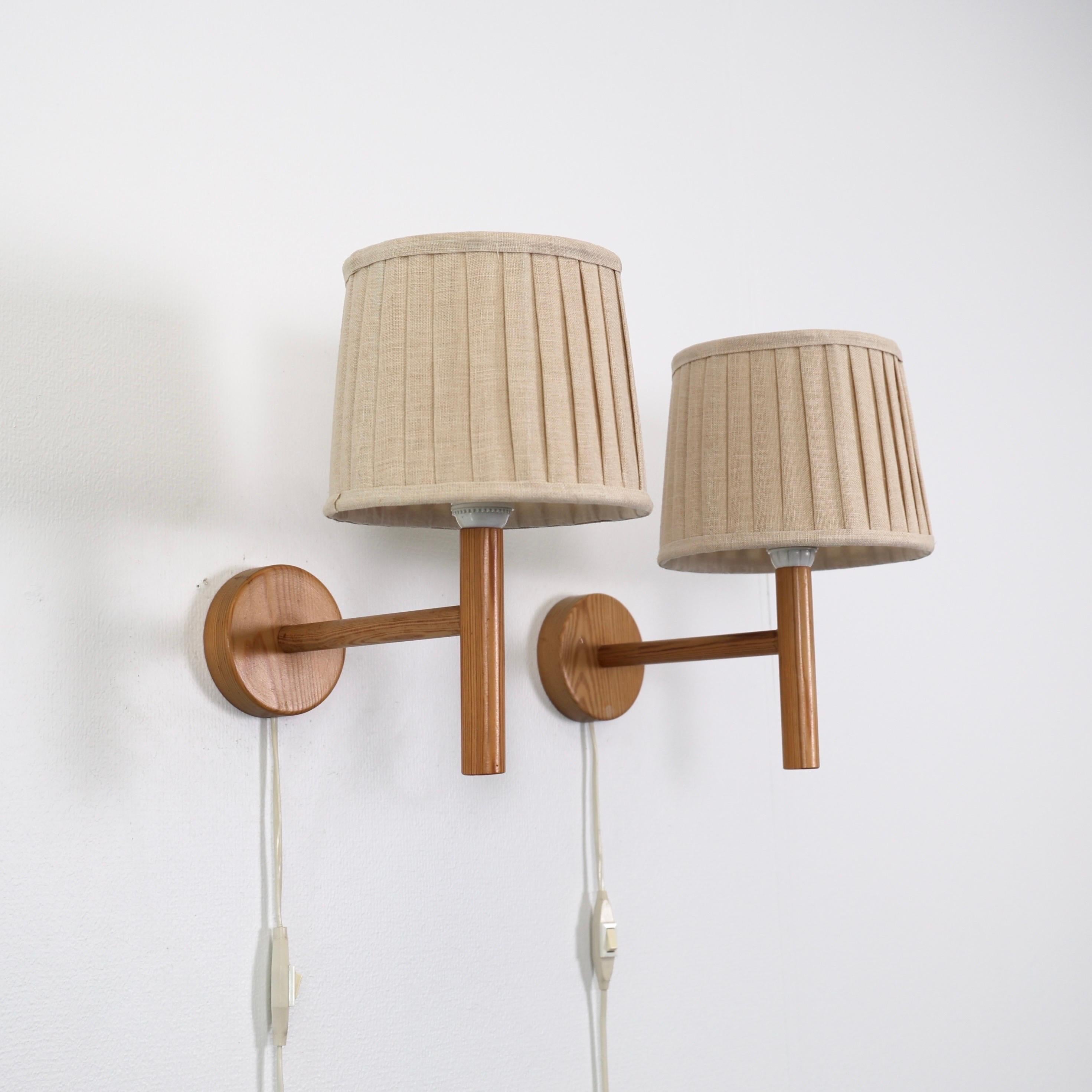 Set Schwedische Moderne Kiefer Holz Wandlampen von Solbackens Svarveri in den 1970er Jahren gemacht. Ein skandinavischer Touch für ein schönes Zuhause.

* Ein Paar (2) Wandleuchter aus Kiefernholz mit cremefarbenen Stoffschirmen
* Hersteller: