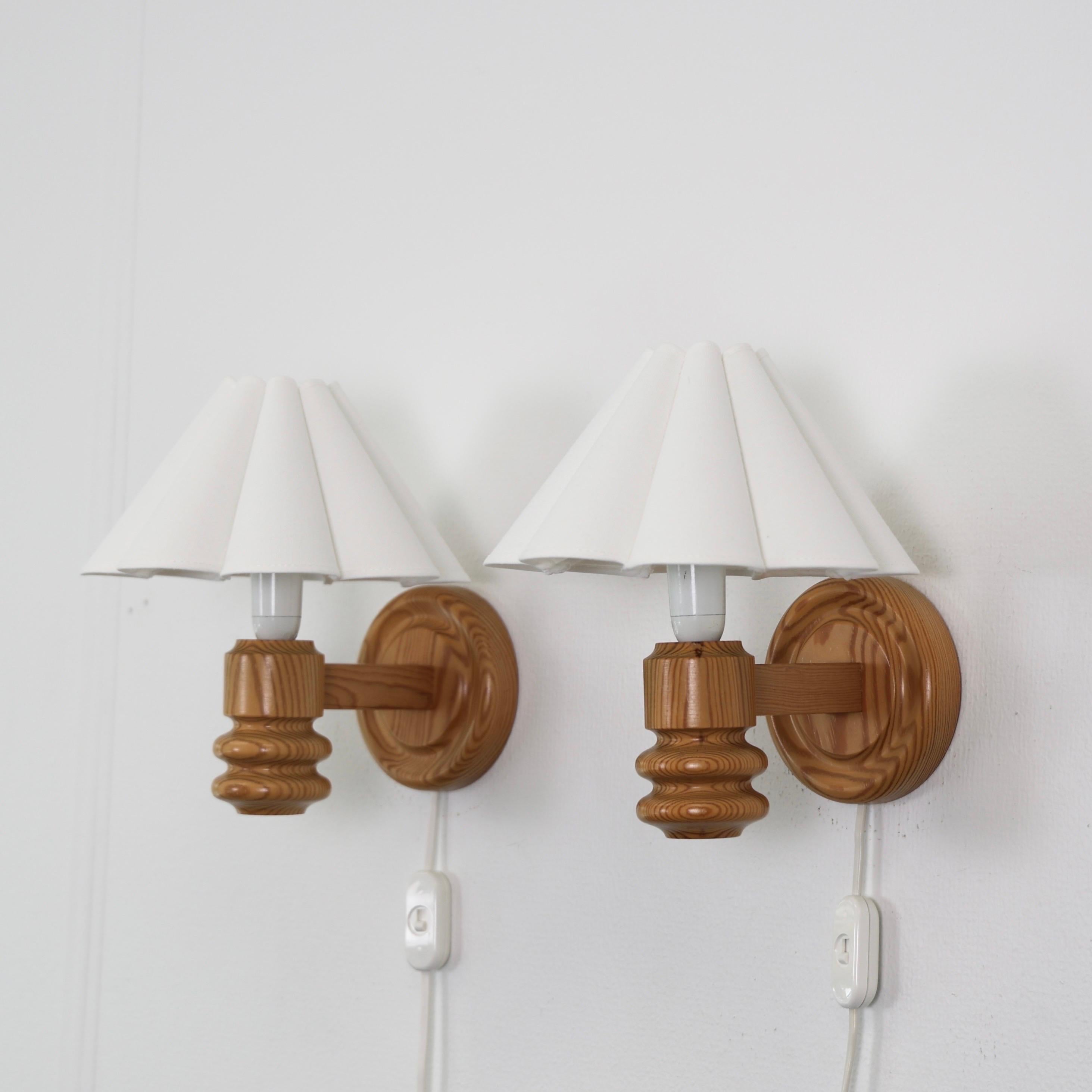 Swedish Modern Pine Wood Wall lamps made by Solbackens Svarveri in the 1970s. 

* Set (2) of pine wood sconces with white fabric clip-on shades.
* Manufacturer: Solbackens Svarveri, Sweden
* Style: 1461
* Year: circa 1970s
* Condition: Good vintage