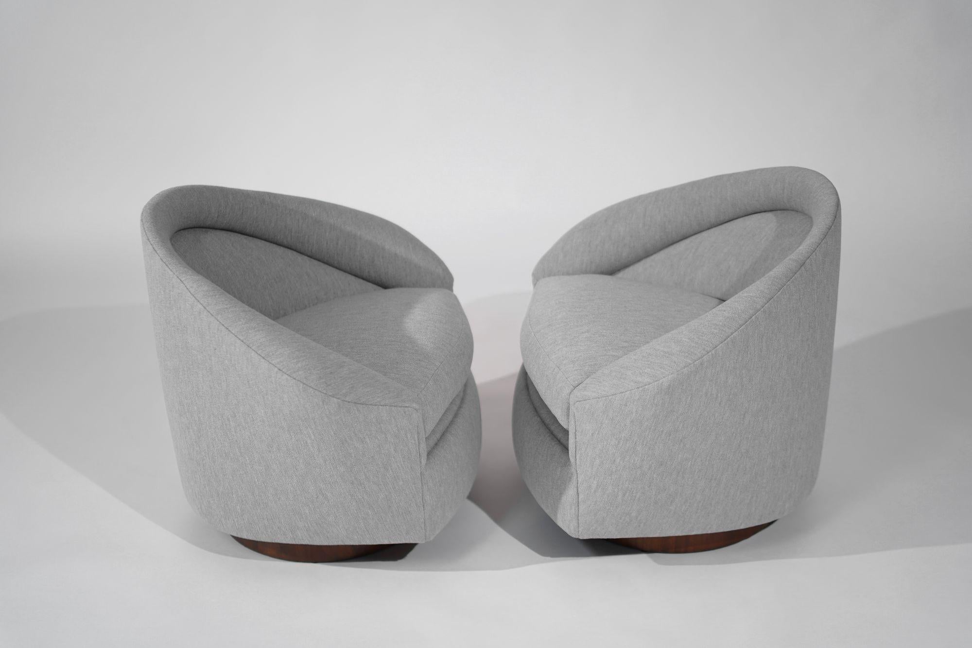 Craft Associates presents a rare find: a set of restored Adrian Pearsall swivel lounge chairs from the 1950s. Upholstered in luxurious gray boucle by Holly Hunt, these chairs swivel and tilt for comfort and versatility. The walnut support has been