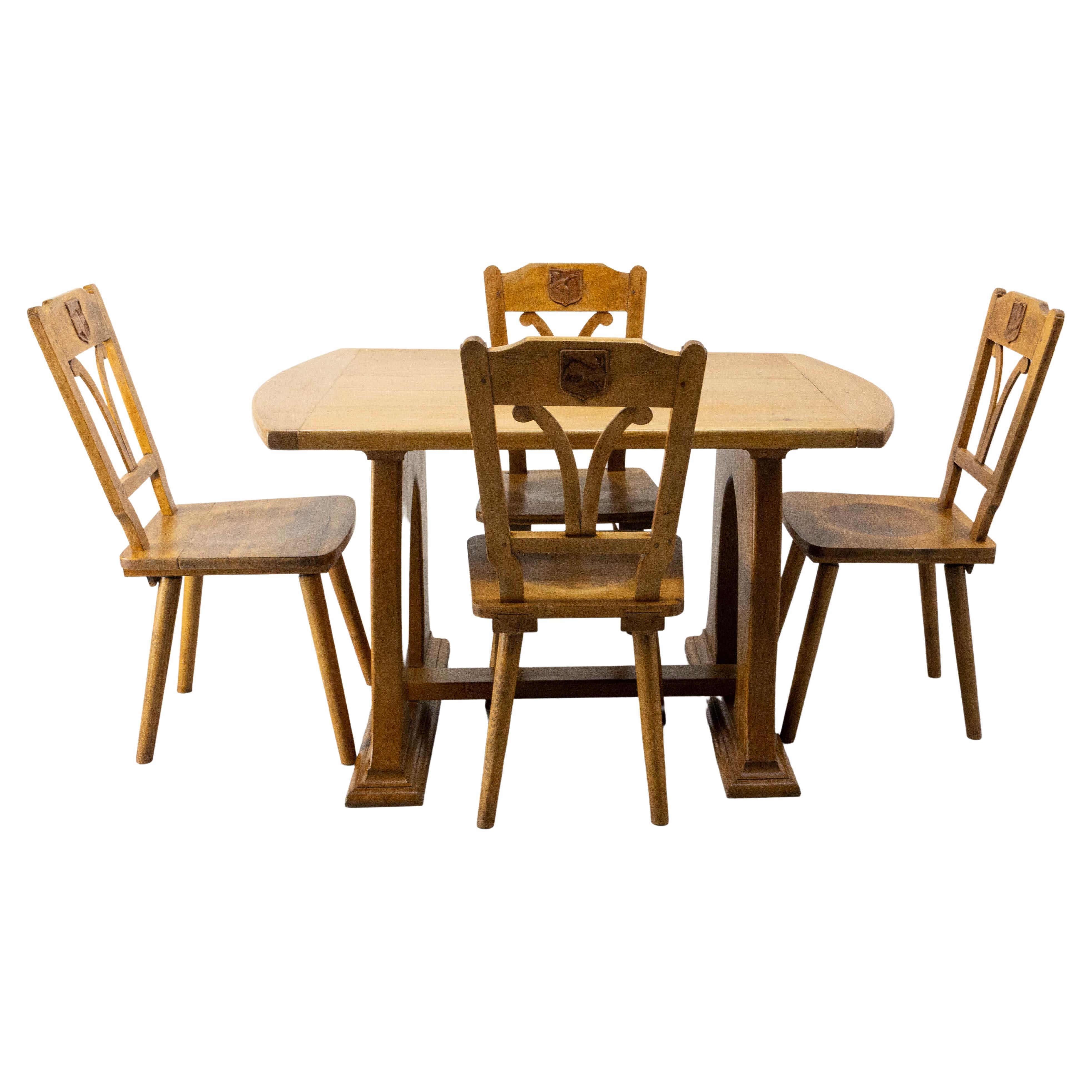French set of a oak table and its four chairs, circa 1960.
The shape of the chairs and table are inspired by the lines of art nouveau. On the back of each chair, integrated into a frame in the form of a blazon, are two sculptures (one at the front