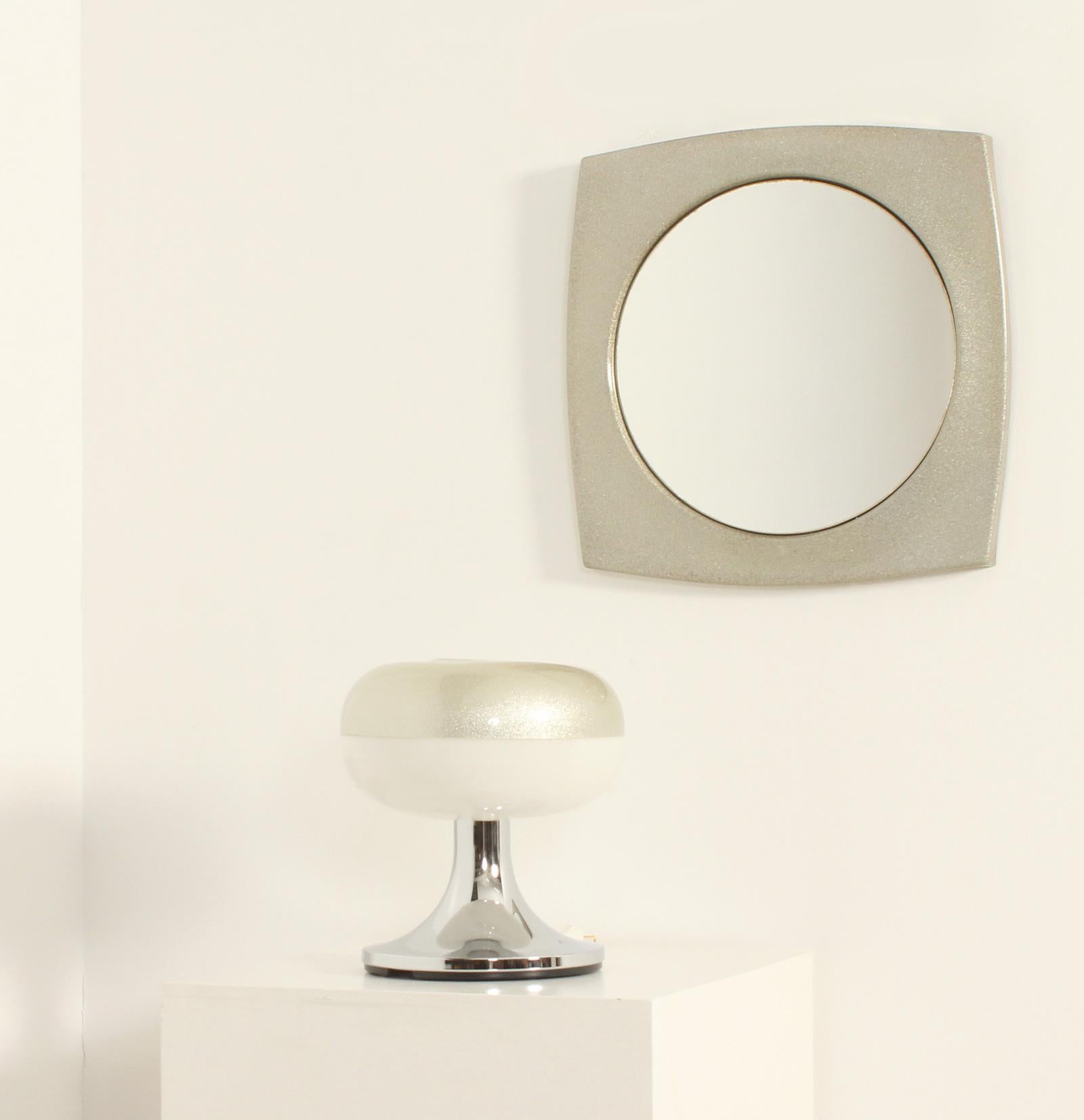 Conjunto de lámpara de mesa y espejo de los años 70, España. Fabricada en fibra de vidrio con incrustaciones metálicas, reflector de la lámpara en acrílico blanco y base de metal cromado. 