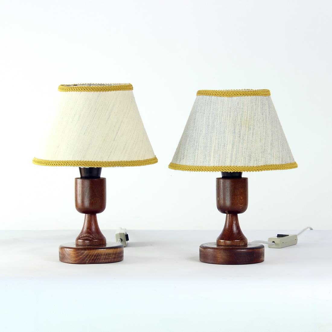 Set of two table lamps produced in Czechoslovakia in 1960s. The lamps have a wooden base in dark oak. The shield is on a wire construction and has a paper shield covered with fabric. The fabric is different on each lamp. The fabric is not original,