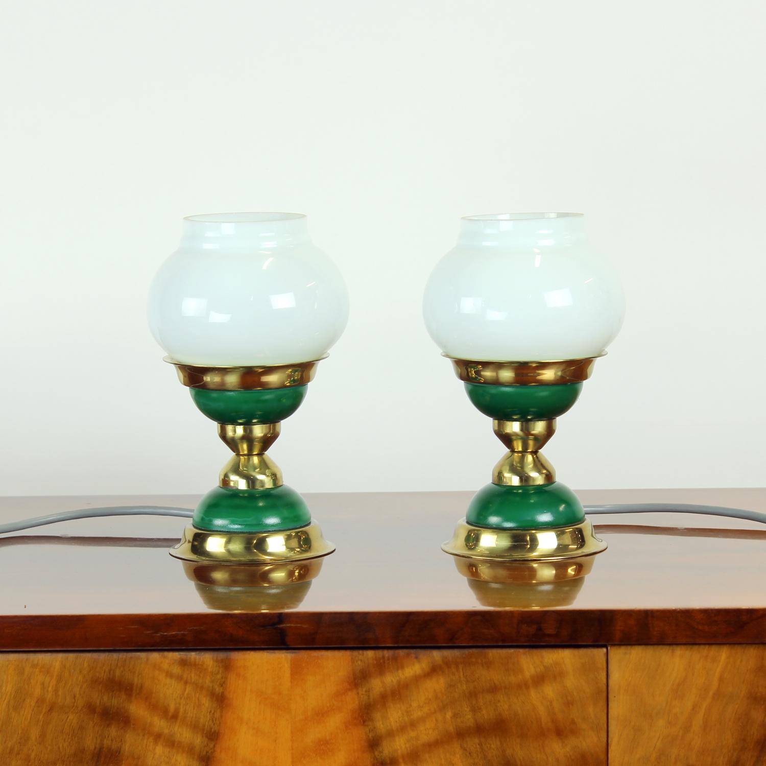 Preciosa pareja de lámparas de sobremesa de mediados de siglo fabricadas en 1955 por Jablonecké Sklárne, Checoslovaquia. Cada lámpara combina metal lacado en verde intenso con cálidos detalles en latón, creando un diseño refinado y atemporal que se