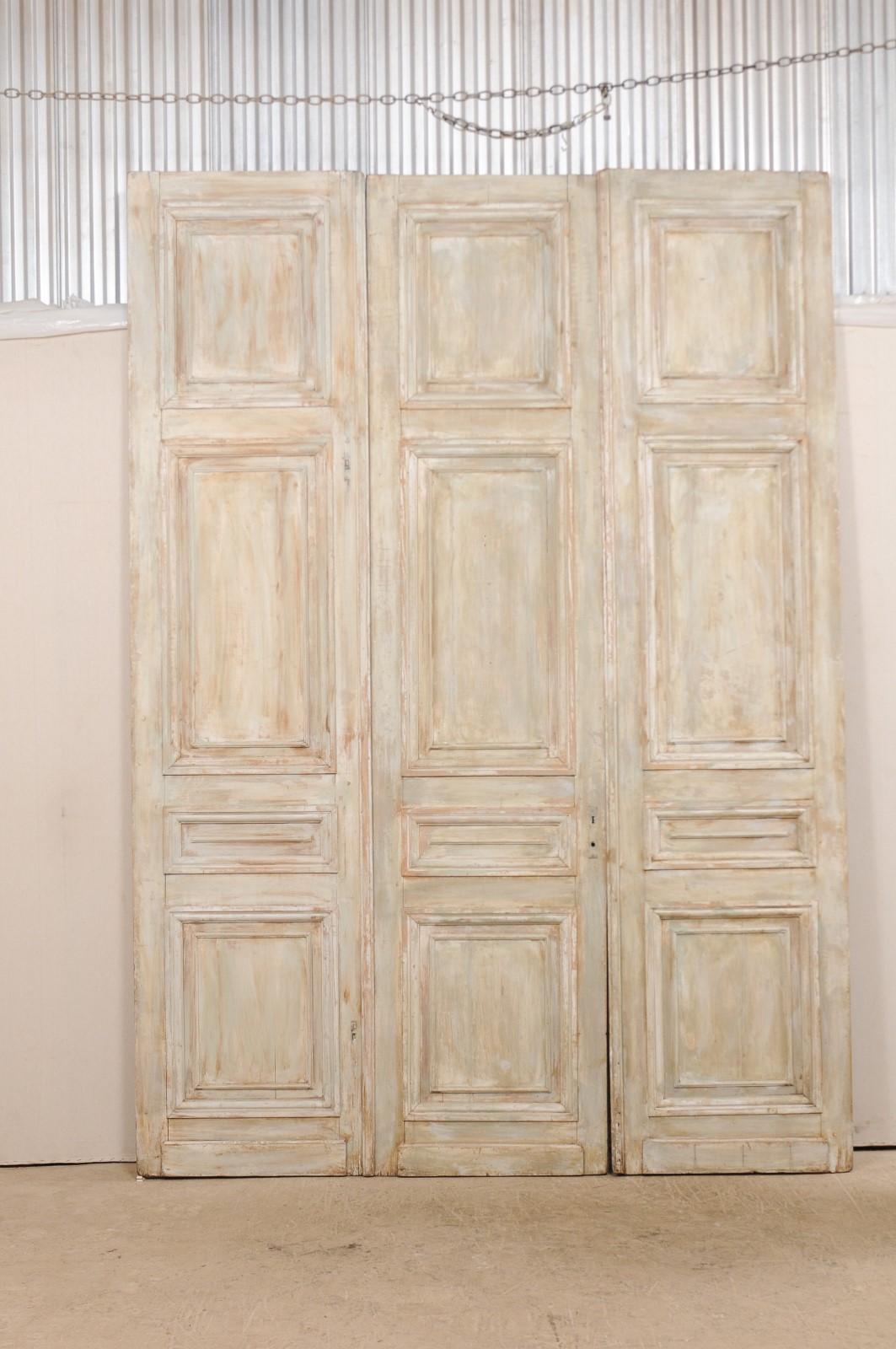 This set of tall doors from the 19th century includes a single stationary door which pairs alongside a doubled, bi-folding door. These lovely antique doors from France each have four molded and recessed panels, adorning both the front and back sides