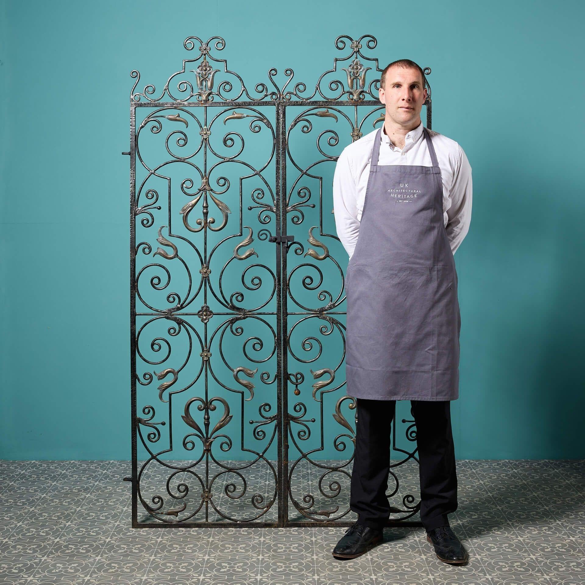 A stunning set of tall handcrafted wrought iron reclaimed garden gates, traditionally made by a skilled 20th century blacksmith. With an abundance of ornate scrollwork highlighted with bronze details, these garden side gates are a timeless addition