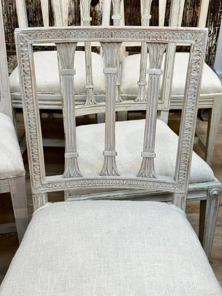 Ten 18th century Swedish side chairs, off-white, eight of the same design, two similar, grouped as ten. Varying sizes, measures: height from 33.5-35”, width 16” – 18”, depth 16”, seat height 17.5-18”. Newly upholstered.