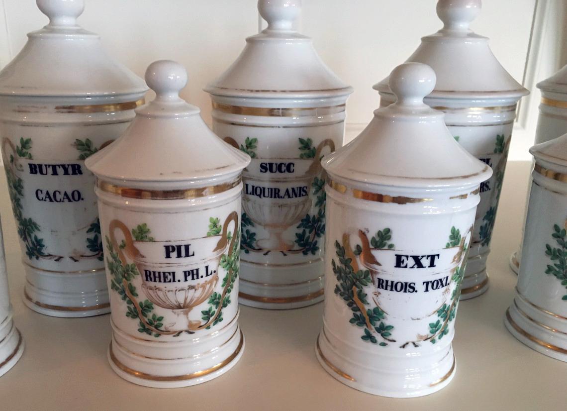 Set of ten French Porcelain apothecary jars,
19th century.

The set consists of five smaller cover jars and five larger covered jars. Each has a different description on the front relating to the original contents placed on a gilded painted urn