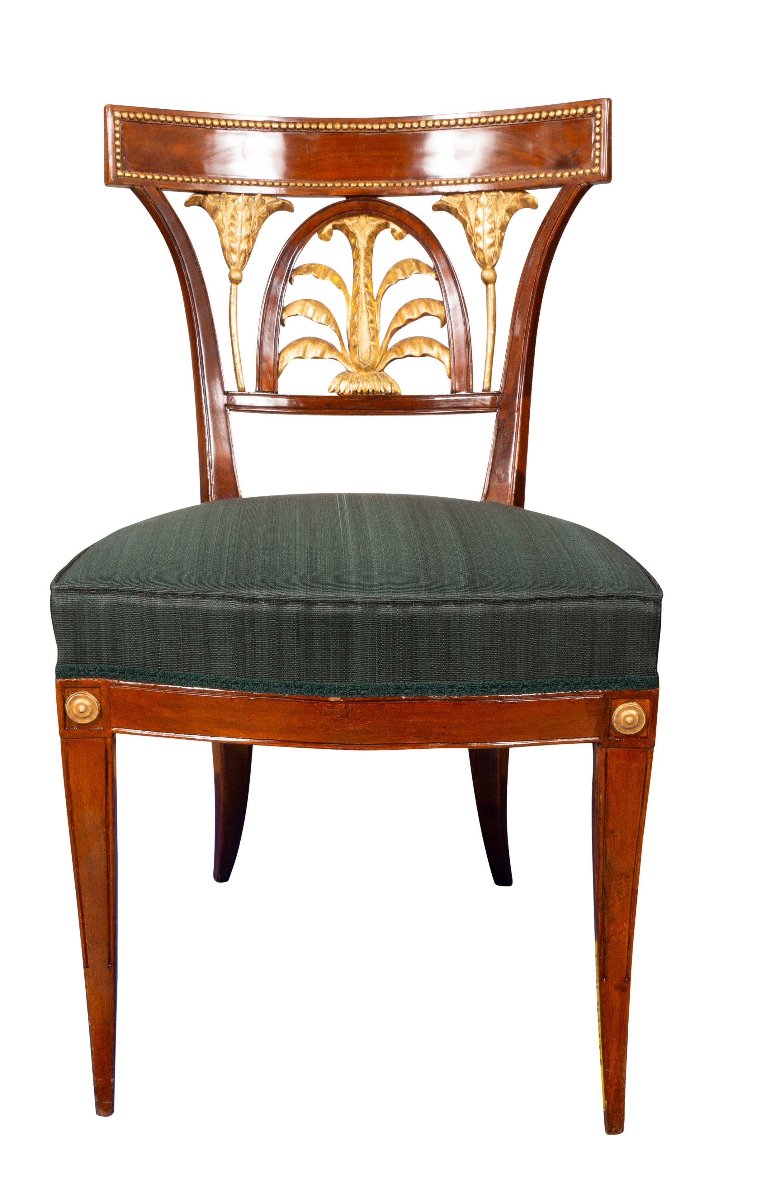 Each with rectangular crest rail with gilt beaded border over a carved and beautifully water gilded anthemion shaped splat flanked by stems and leaves. Upholstered seat raised on slightly curved square tapered legs headed by gilt roundels. From a