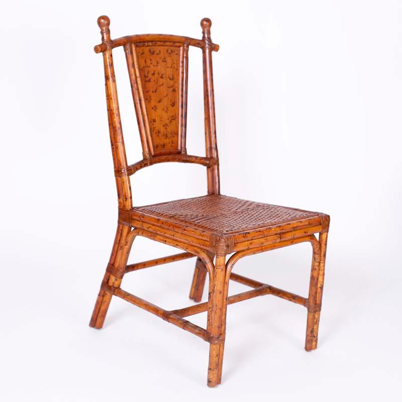 Mid-century set of ten British Colonial bamboo dining chairs with a burnt finish, reed wrapped joints, wicker seats and hand decorated back panels.