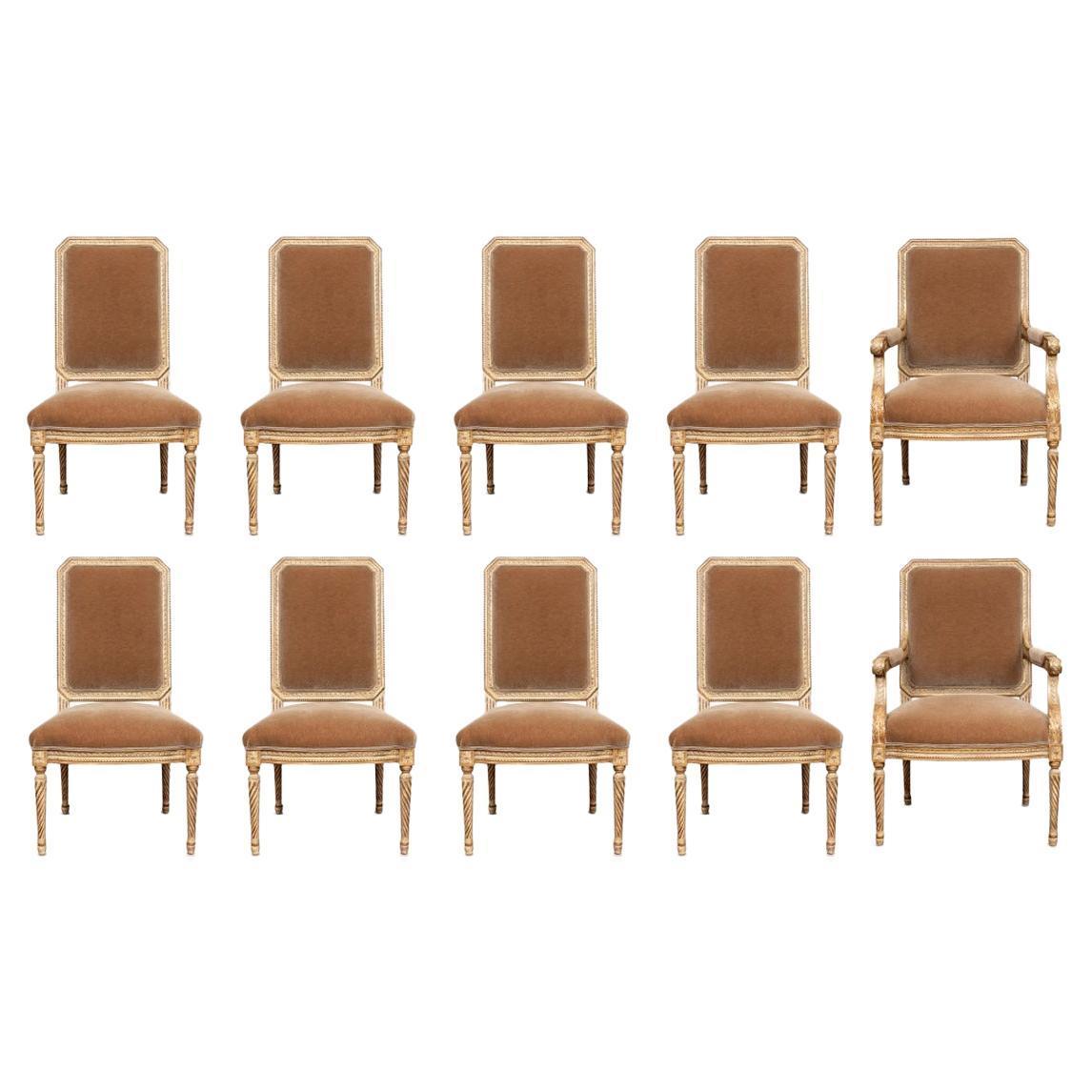 Collection of ten fine quality upholstered and carved dining chairs featuring chamfered top rail with carved frame with gilt accents on turned fluted tapered round legs. Upholstered in mohair. Collection includes two arm chairs and eight side