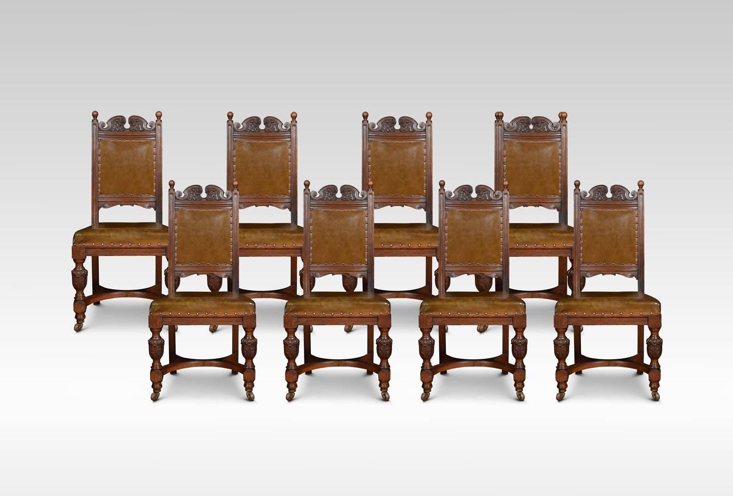 Set of ten carved oak dining chairs, consisting of two carver armchairs, and eight side chairs, each with scrolling foliated cresting rails, padded backs and stuffover seats, each raised upon lobed fluted vase supports and casters joined by shaped