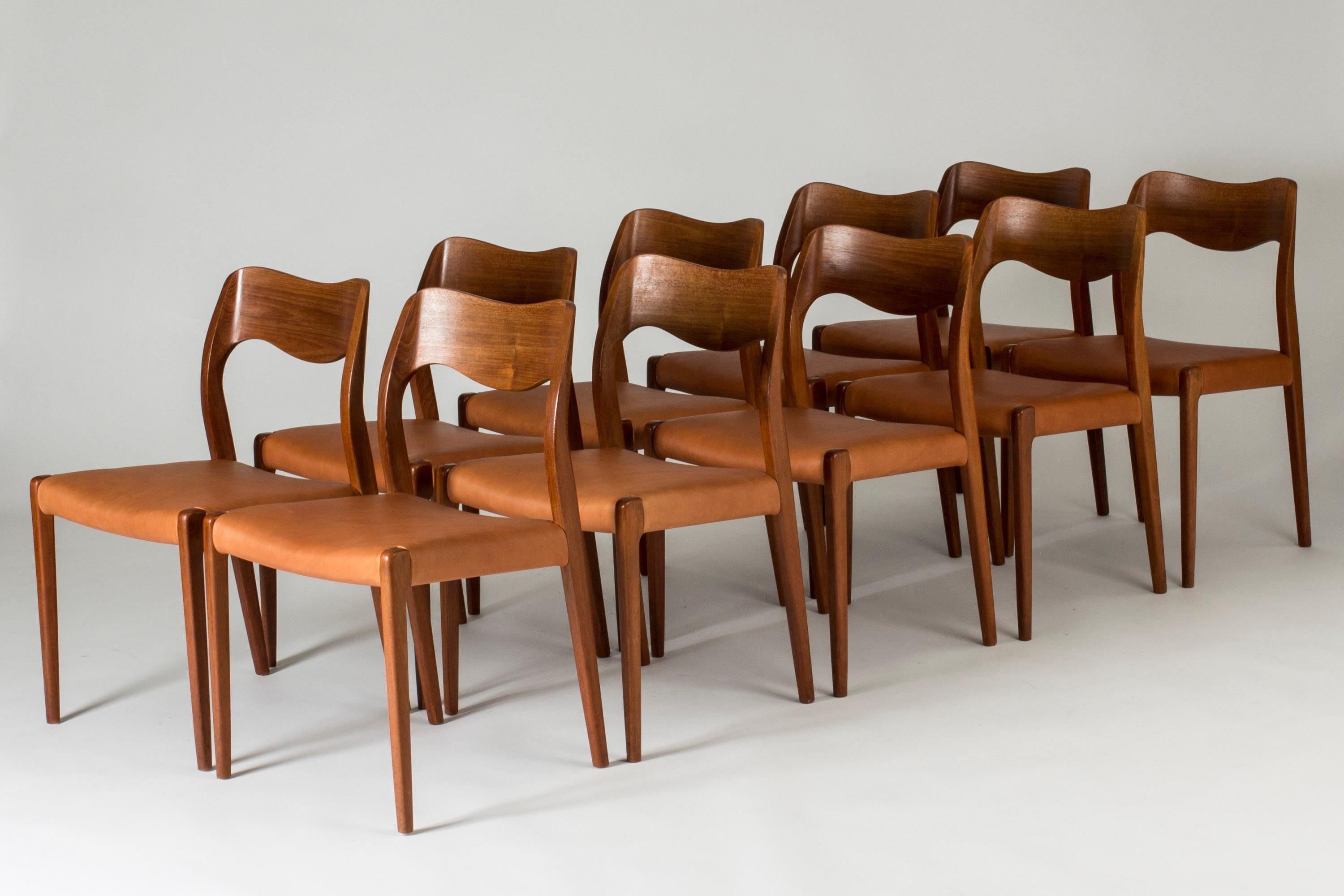 Set of ten beautiful dining chairs by Niels O. Møller, made from teak with supple cognac leather seats. The elegant backrests curve in wave shapes, accentuating the wood grain.