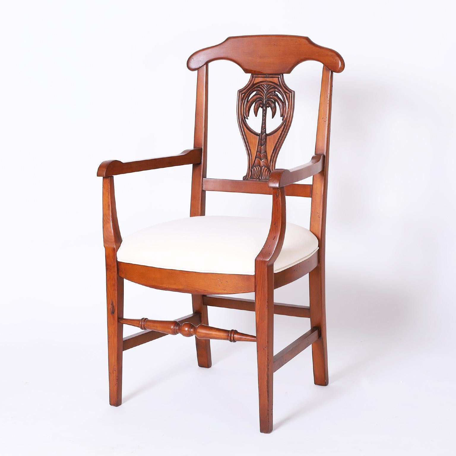 Set of ten dining chairs, two arm and eight side, crafted in mahogany with a tropical motif having palm tree carvings on the backs, comfortable upholstered seats, and tapered front legs with turned stretchers.

Armchairs H: 40.5 W: 22 D: 22 SH: