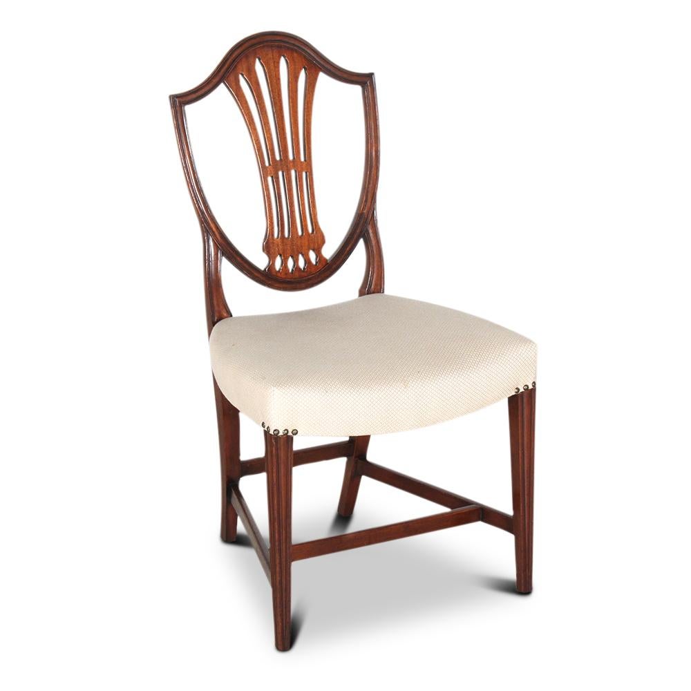 A set of ten solid mahogany English George III style shield back dining chairs, the backs with pierced splats, the legs of a simple tapering design.
Comfortable and sturdy chairs suitable for daily use.
Neutral-colored fabric in very good