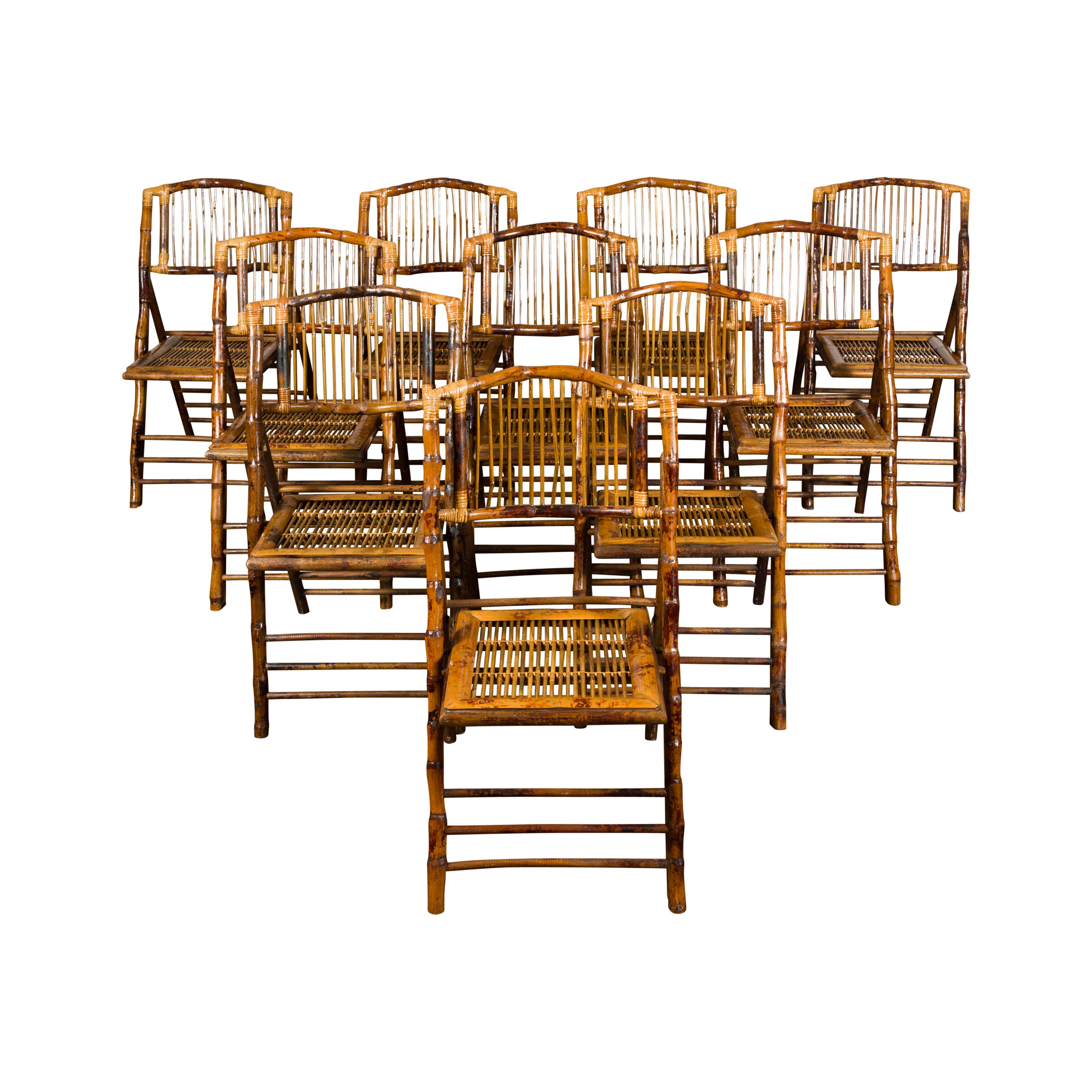 A set of ten English vintage bamboo folding side chairs from the mid-20th century, with slatted backs and rattan accents. Charming us with their rustic presence and nice patina, this set of ten midcentury bamboo folding side chairs features slightly