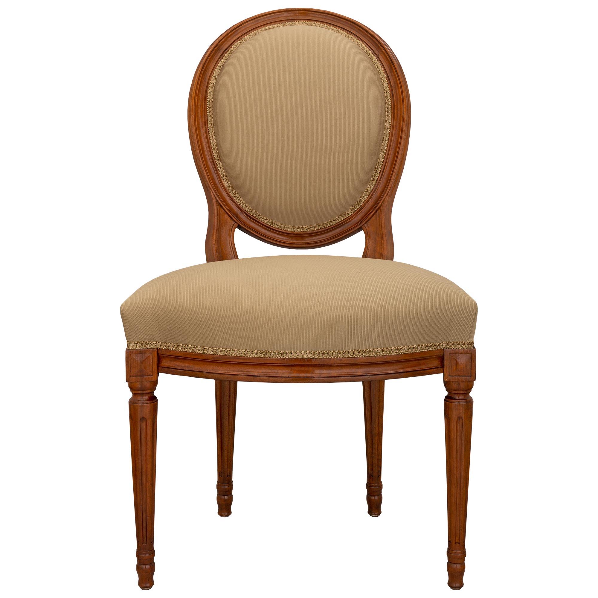 A most elegant and complete set of ten French turn of the century Louis XVI st. walnut dining chairs. Each chair is raised by fine circular fluted tapered legs with lovely topie shaped feet. Above each leg are carved block reserves flanking the