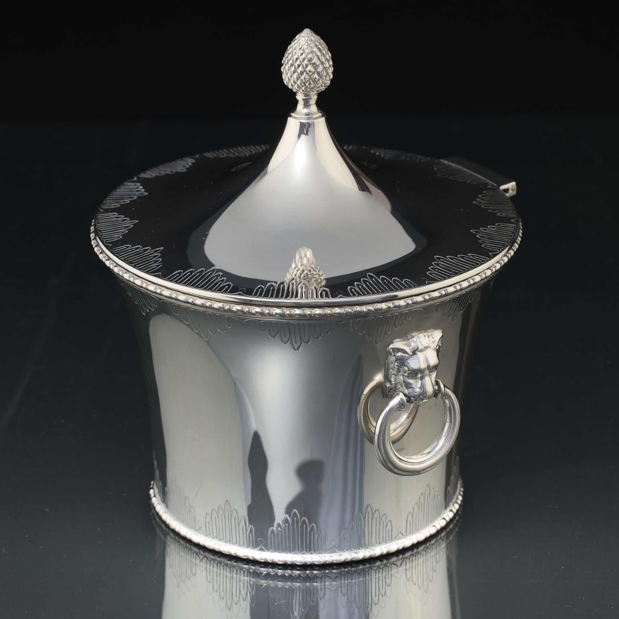Silver biscuit box of tapering cylindrical form, fitted with a hinged conical cover, hand chased around the edge with panels of graduated, stepped fluting, and surmounted by a pineapple-shaped finial; a symbol of hospitality. The silver body is
