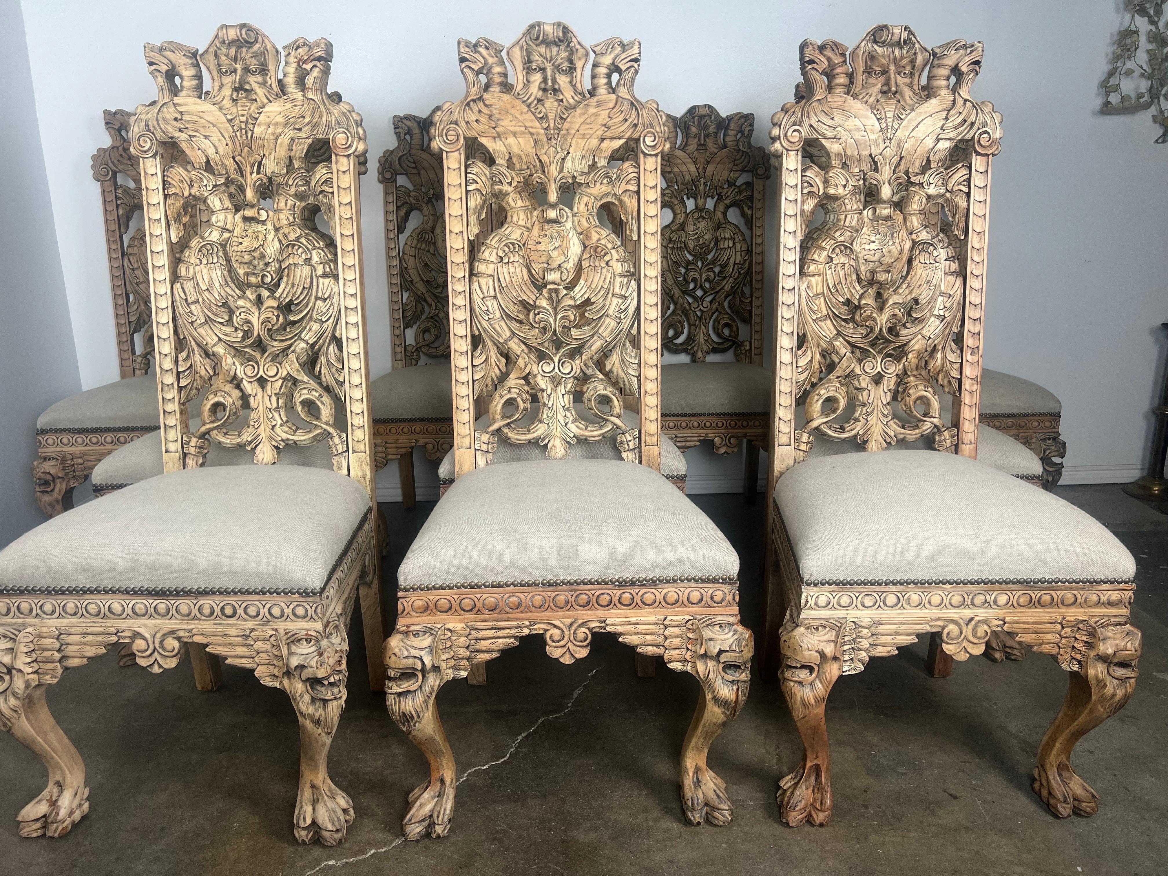 Set of ten English hand carved side dining chairs depicting intricate carved details throughout.  The chairs stand on four cabriole legs that end in lion's paw feet.  The chairs are newly reupholstered in a washed Belgium linen and are detailed with