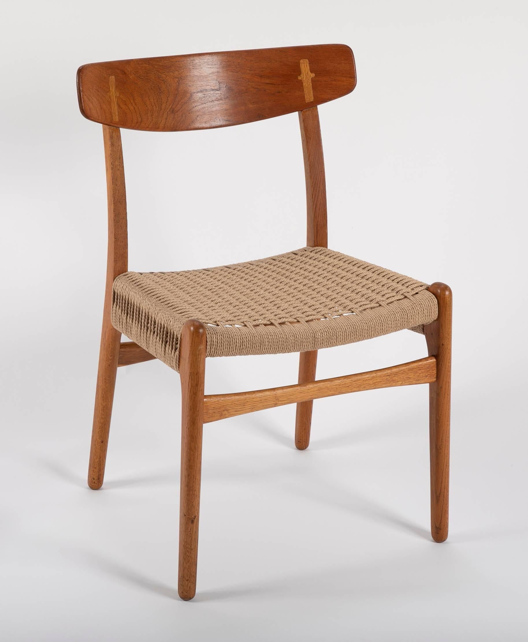 A large set of ten Hans Wegner oak CH-23 dining chairs designed in 1951 and produced by Carl Hansen & Son in Denmark. This set has had all of the seats newly reupholstered using the correct paper coard and seat weaving patter.