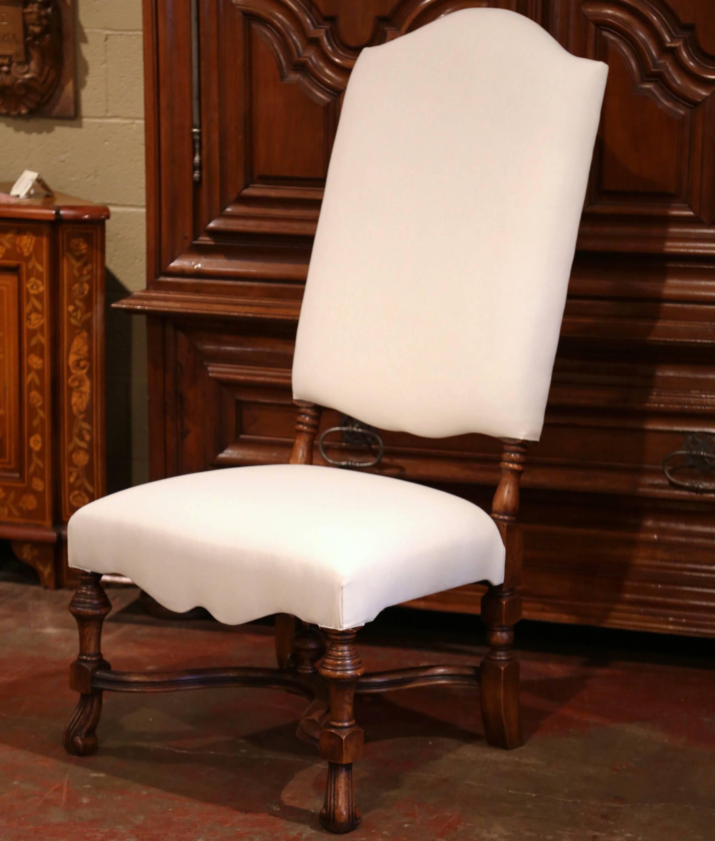 This set of ten walnut dining room chairs would make a sophisticated addition to any dining room. Crafted in France, the chairs are tall, wide and upholstered in a Classic white muslin fabric. Each fruitwood chair features a tall back with an arched