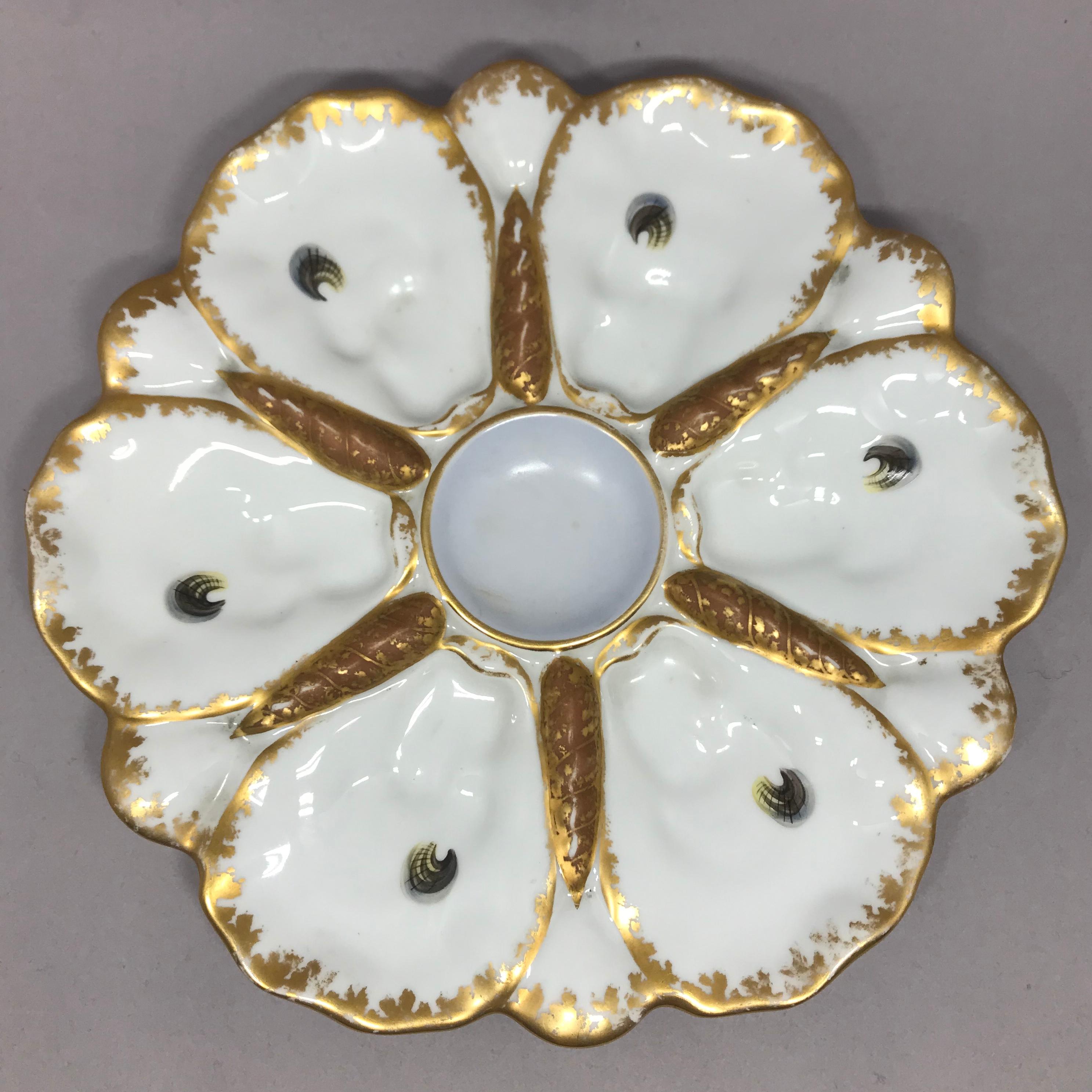 Set of ten Limoges oyster plates. Ten painted and gilt trimmed oyster plates for six oysters with central sauce wells painted in rose (2), violet (3), blue-green (3), and yellow (2). France, circa 1900.
Dimensions: 9.5